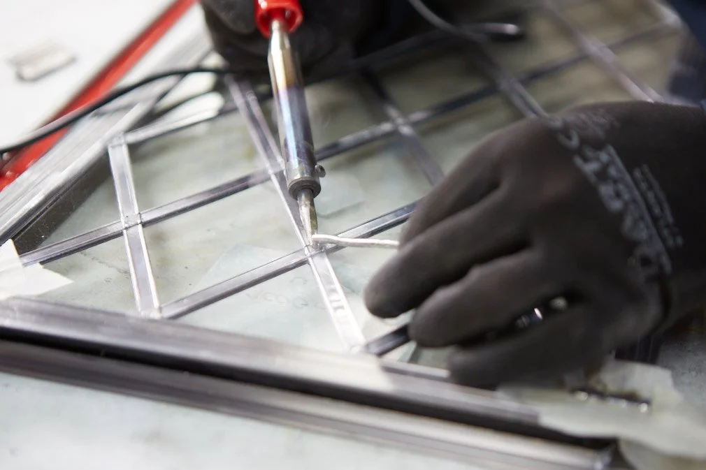 Close-up of a person welding or repairing a metal frame, wearing black gloves and holding a welding tool.