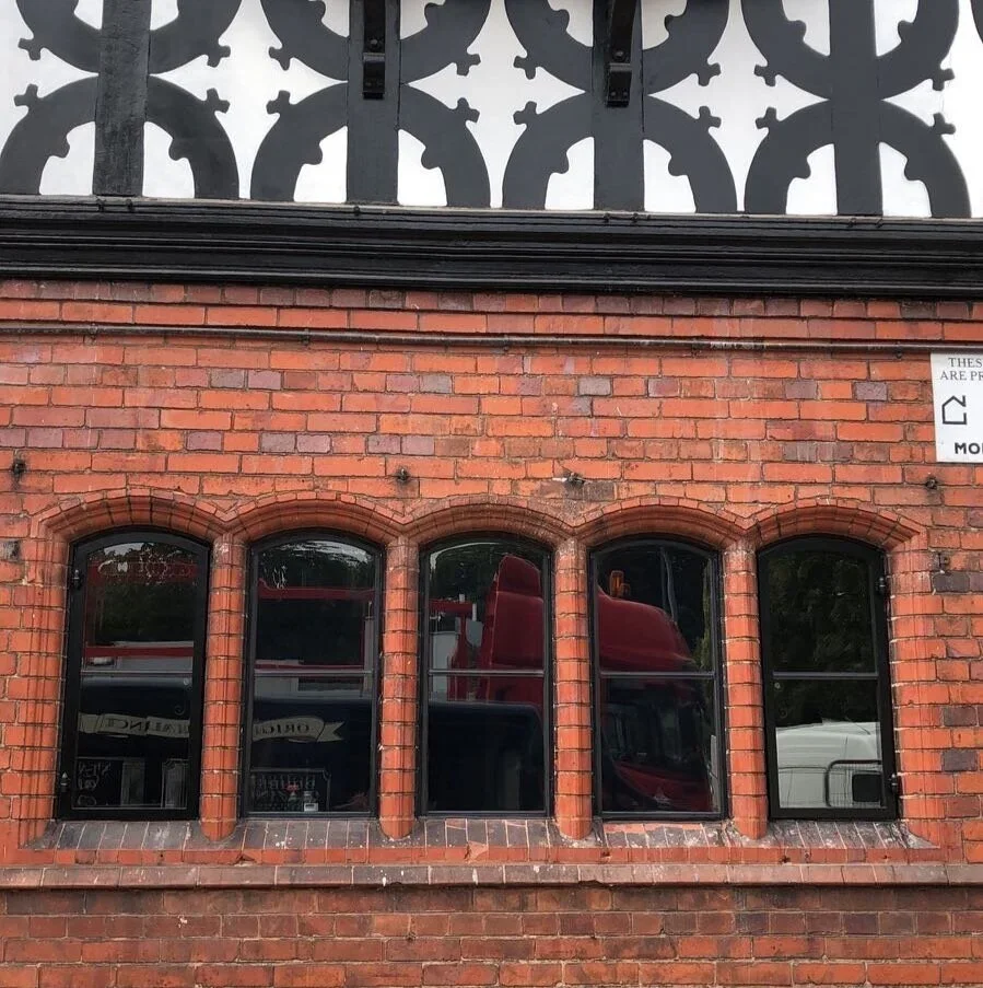Brick building with four arched windows and a black decorative fence above.