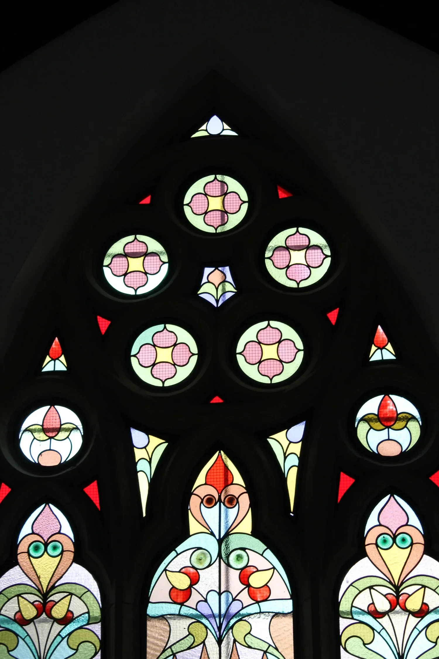 Colorful stained glass window with intricate floral patterns and geometric shapes.