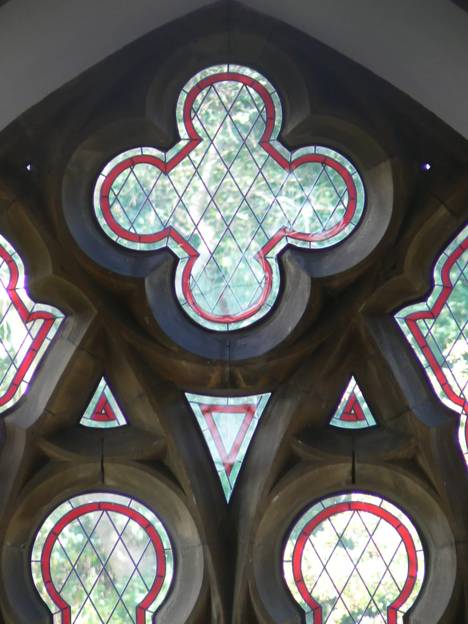 Looking up at ornate stained glass windows with geometric patterns in a church or cathedral.