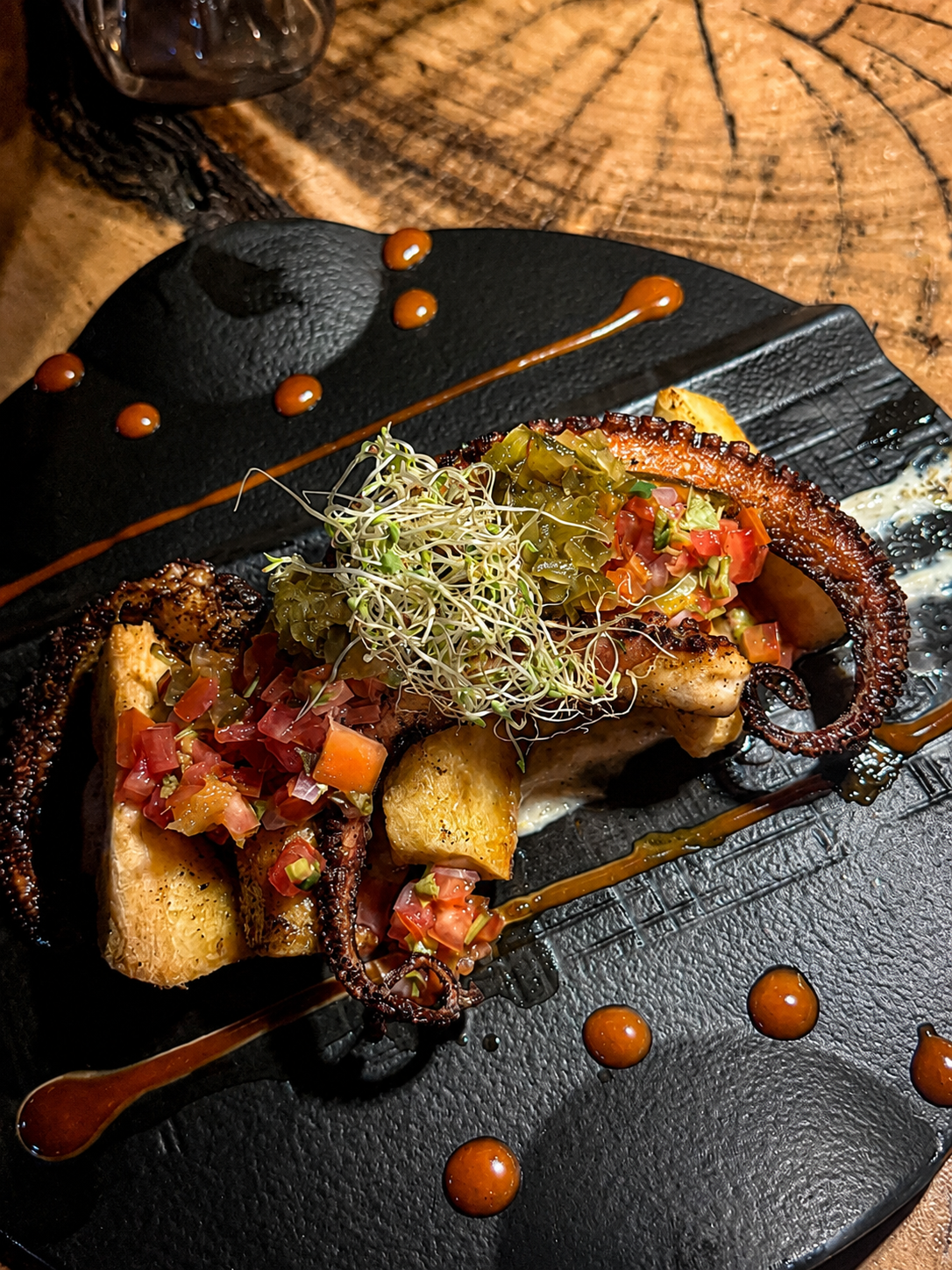 Charred octopus, fried cassava, herb oil, and citrus accents.