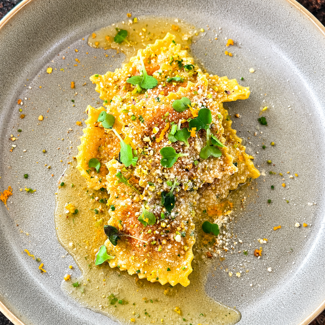 Beet ravioli, brown butter emulsion, toasted pistachio and micro herbs.