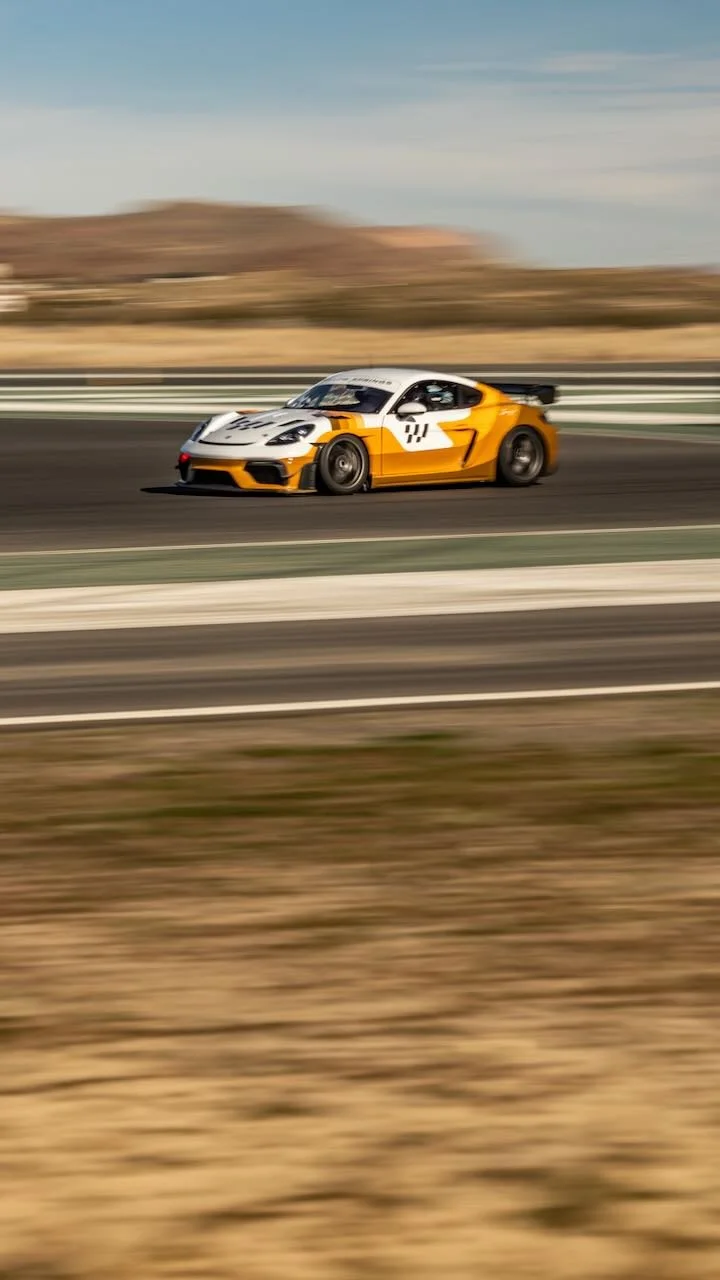 A yellow and white sports car racing on a track, with a blurred background indicating motion.
