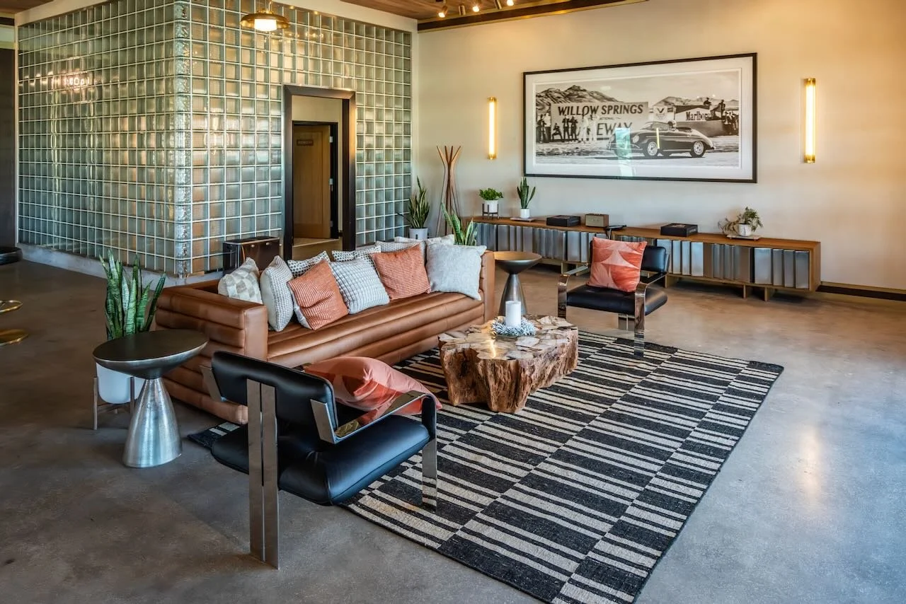Outdoor patio with wooden furniture, beige cushions, a rug, and racetrack view.