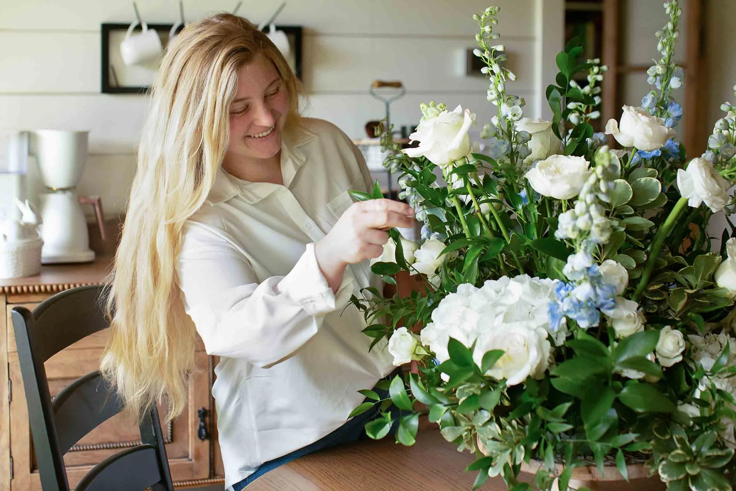 Woman arranging various white flowers in bouquet at Bouquet bar rental in Alexandria Louisiana.