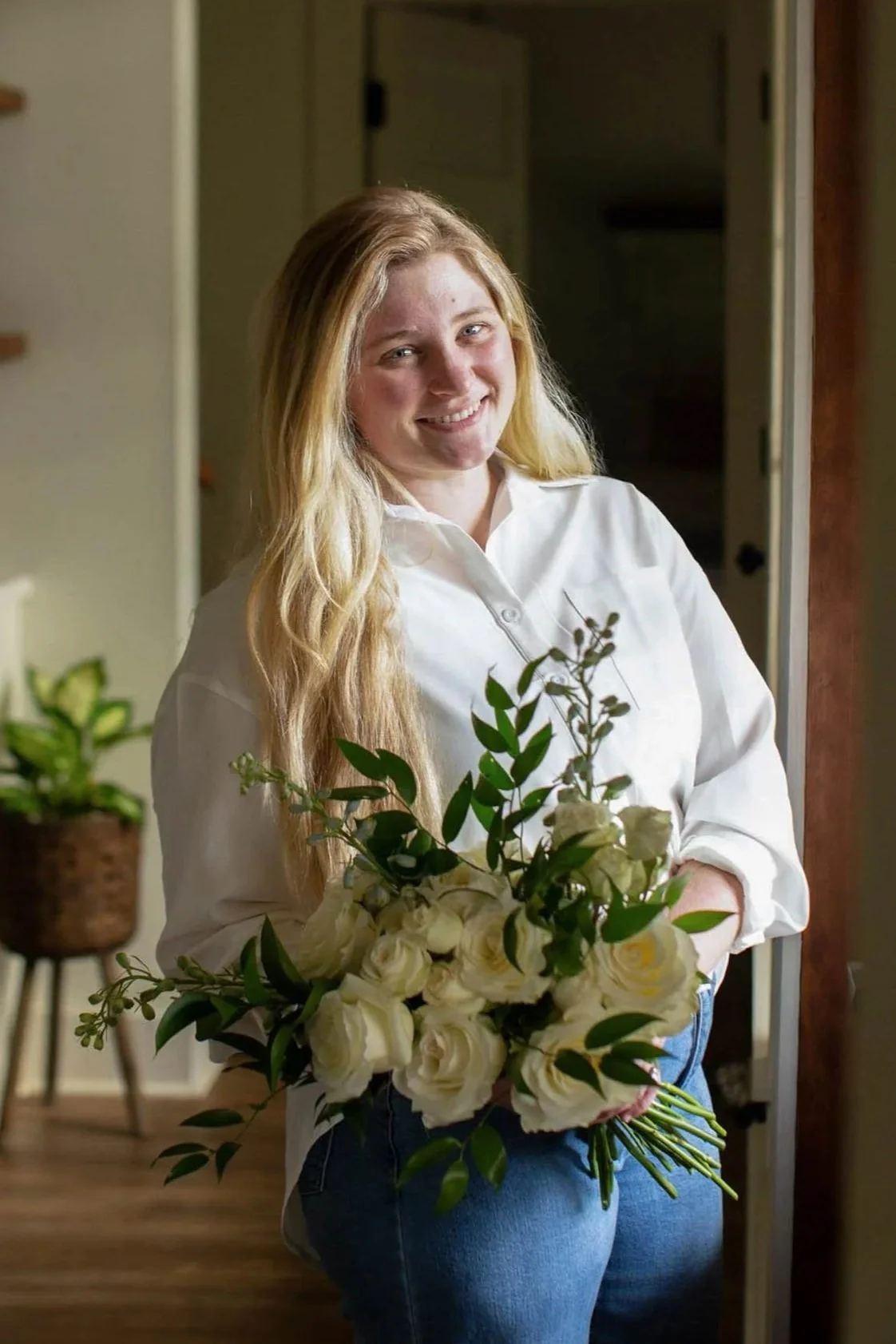 Florist in a white button down holding an elegant wedding bouquet.