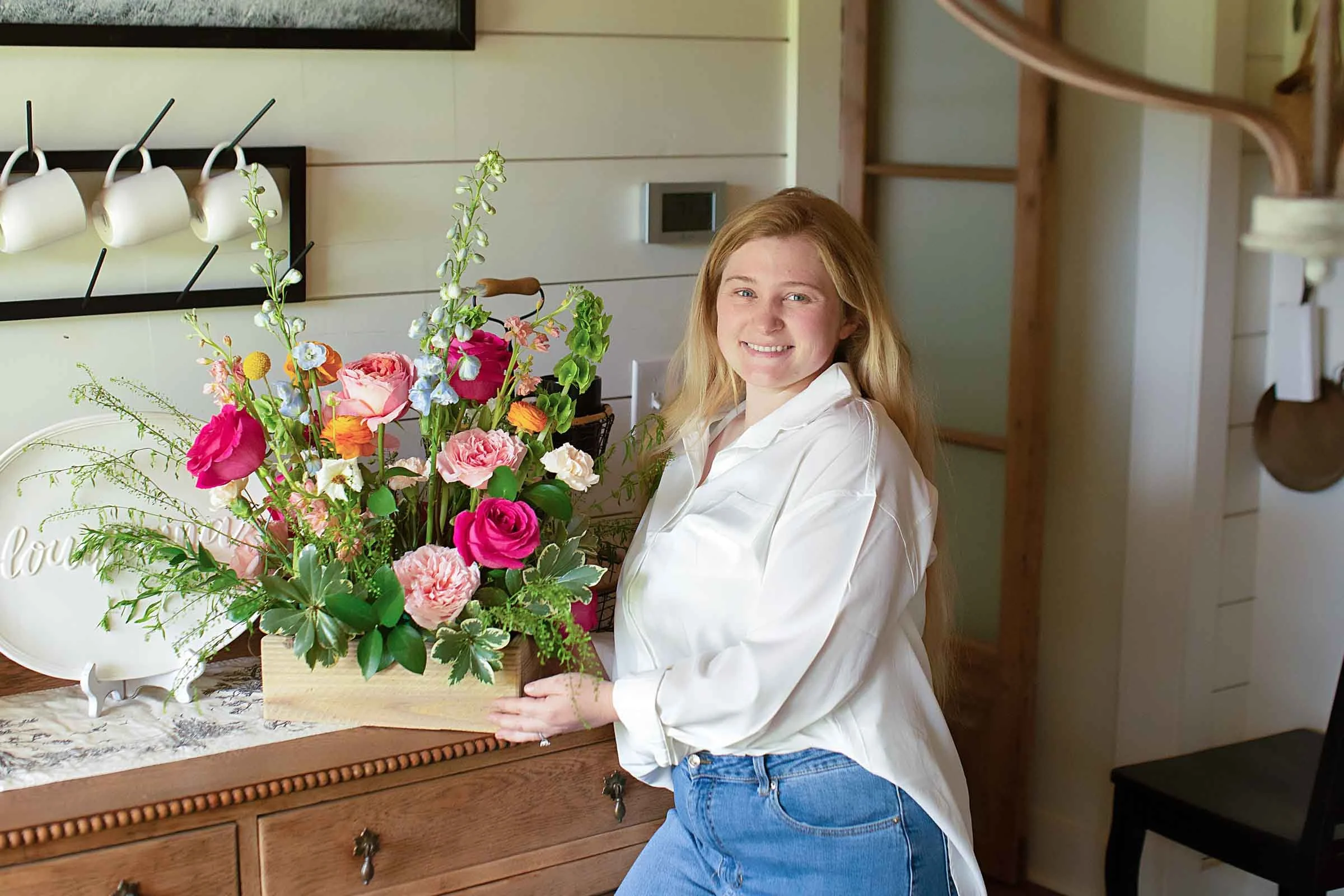 Central Louisiana florist posing by a table with a floral arrangement.