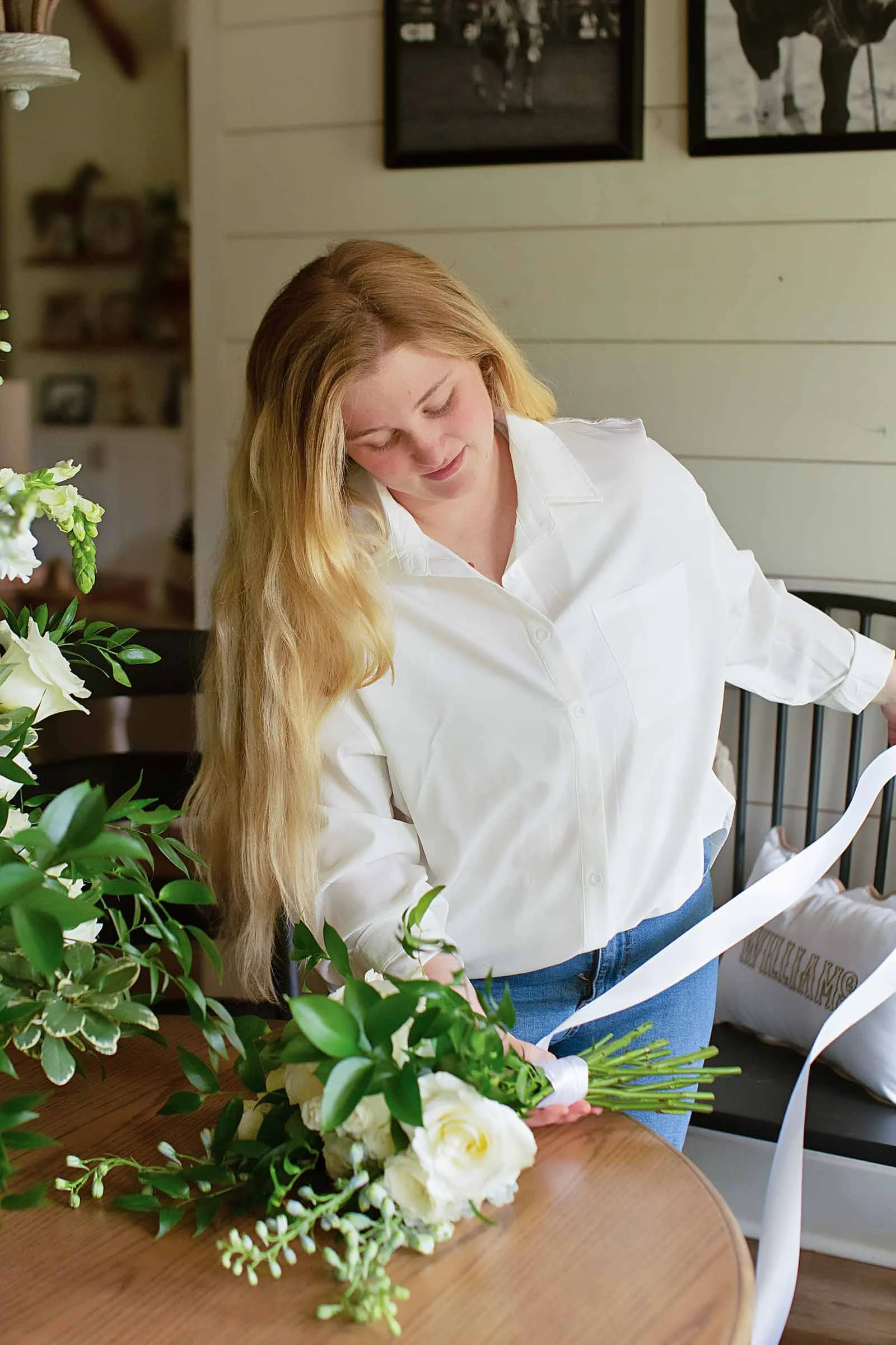Wedding florist tying white ribbon around a white bouquet for a central Louisiana wedding.