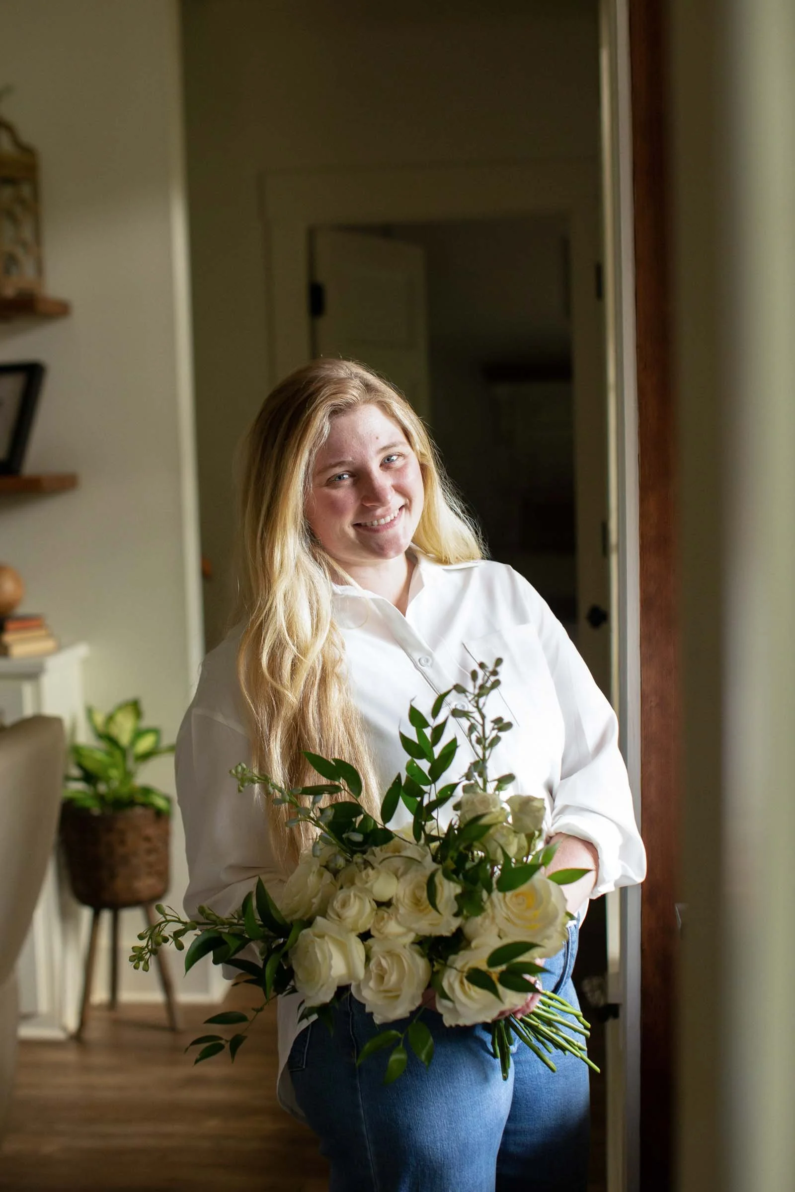 A florist holding a beautiful bouquet, standing in a doorway.