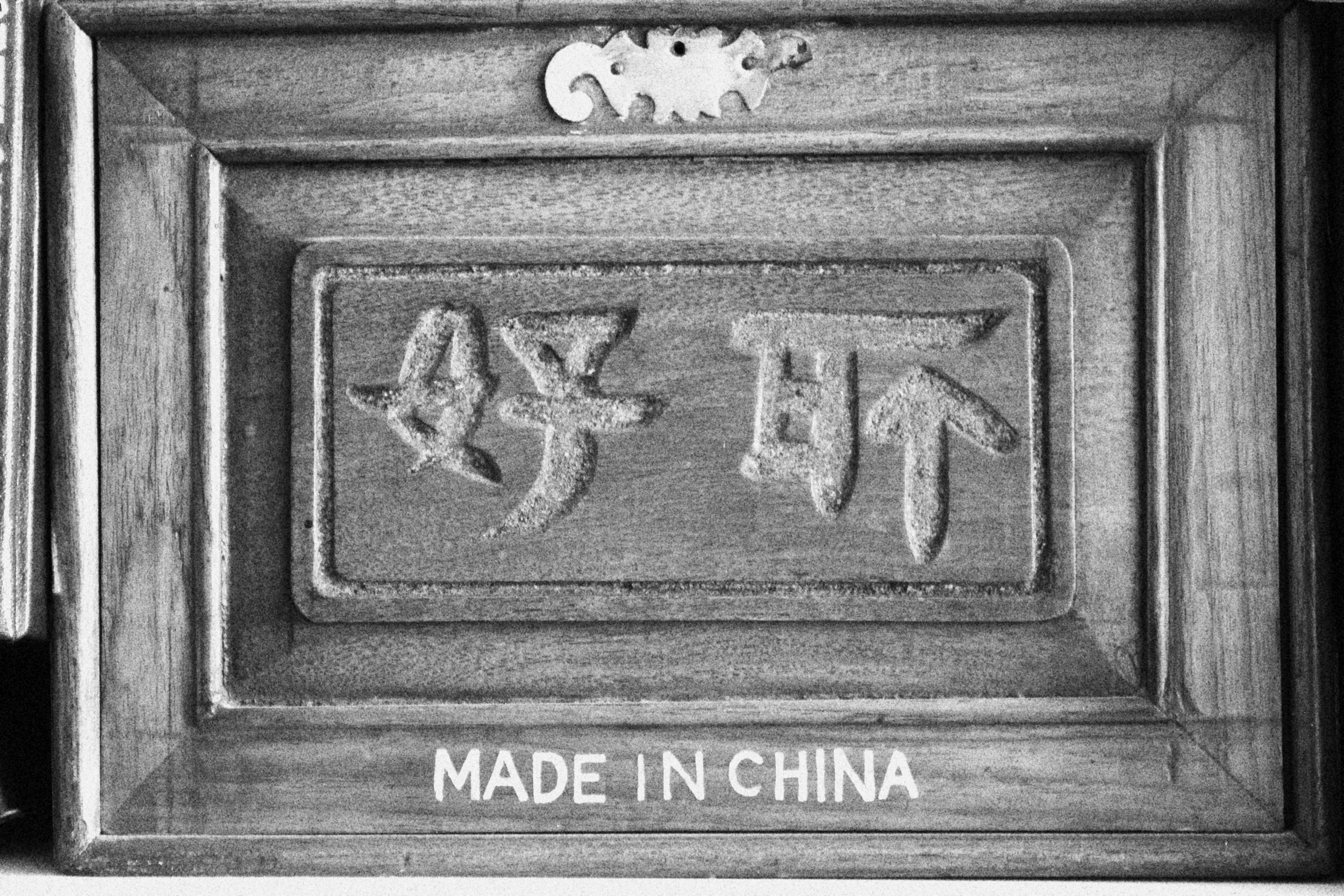 Wooden sign with Chinese characters carved into it, and the text "MADE IN CHINA" at the bottom.