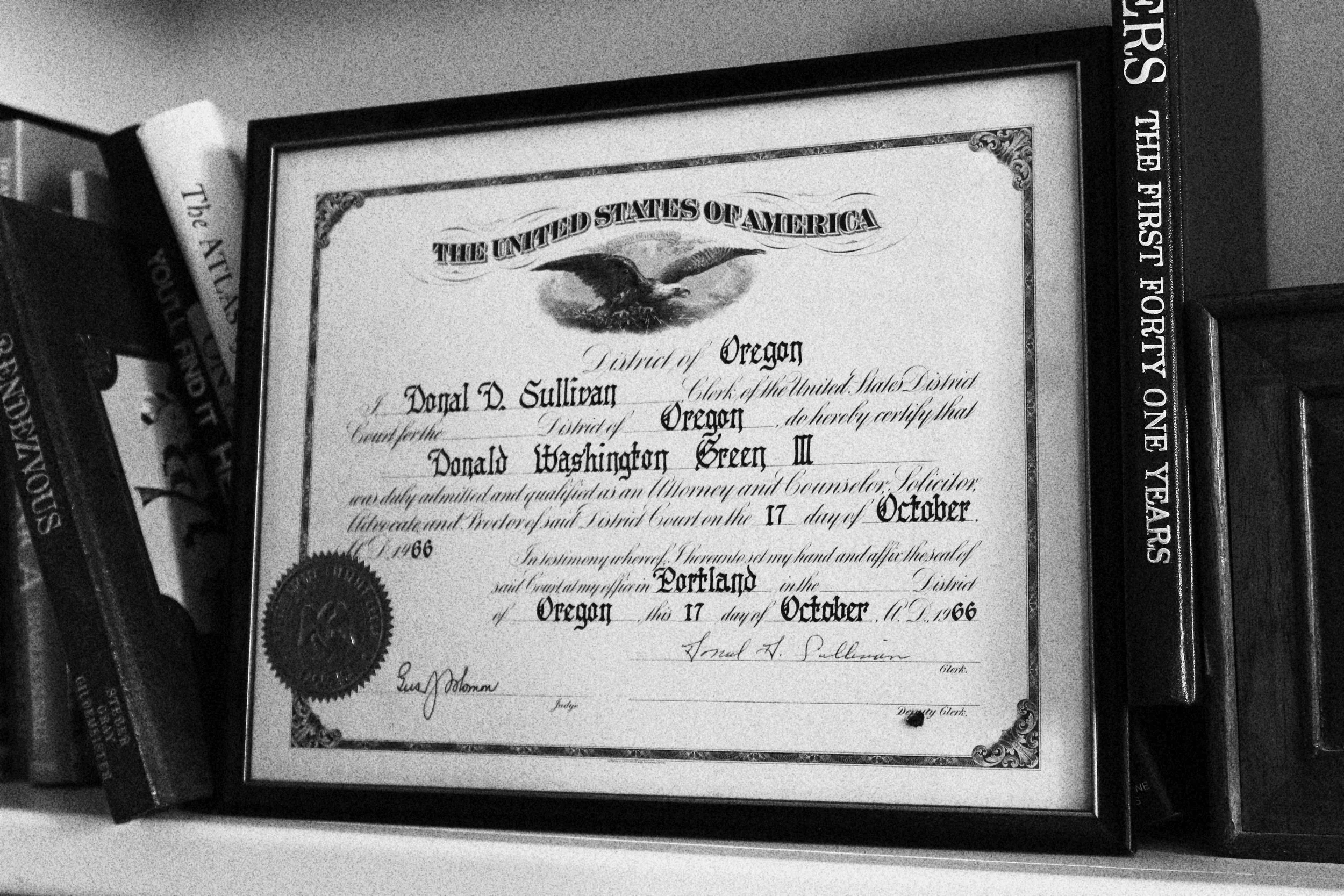 A framed certificate for Donald Washington Green II, a lawyer and counselor, issued in Portland, Oregon, dated October 17, 1966, resting on a shelf among books.