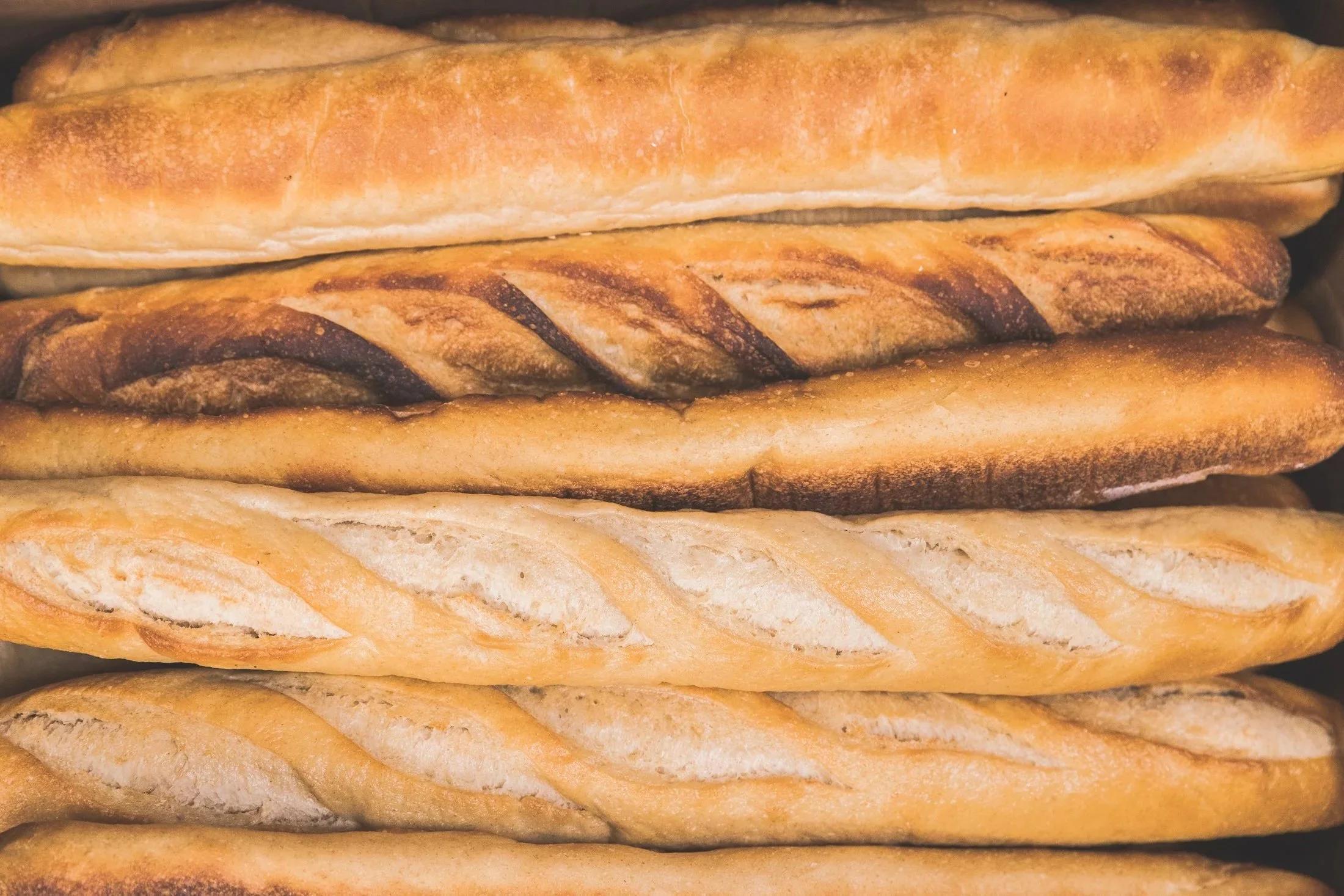 Stacked loaves of baked bread with golden crusts.