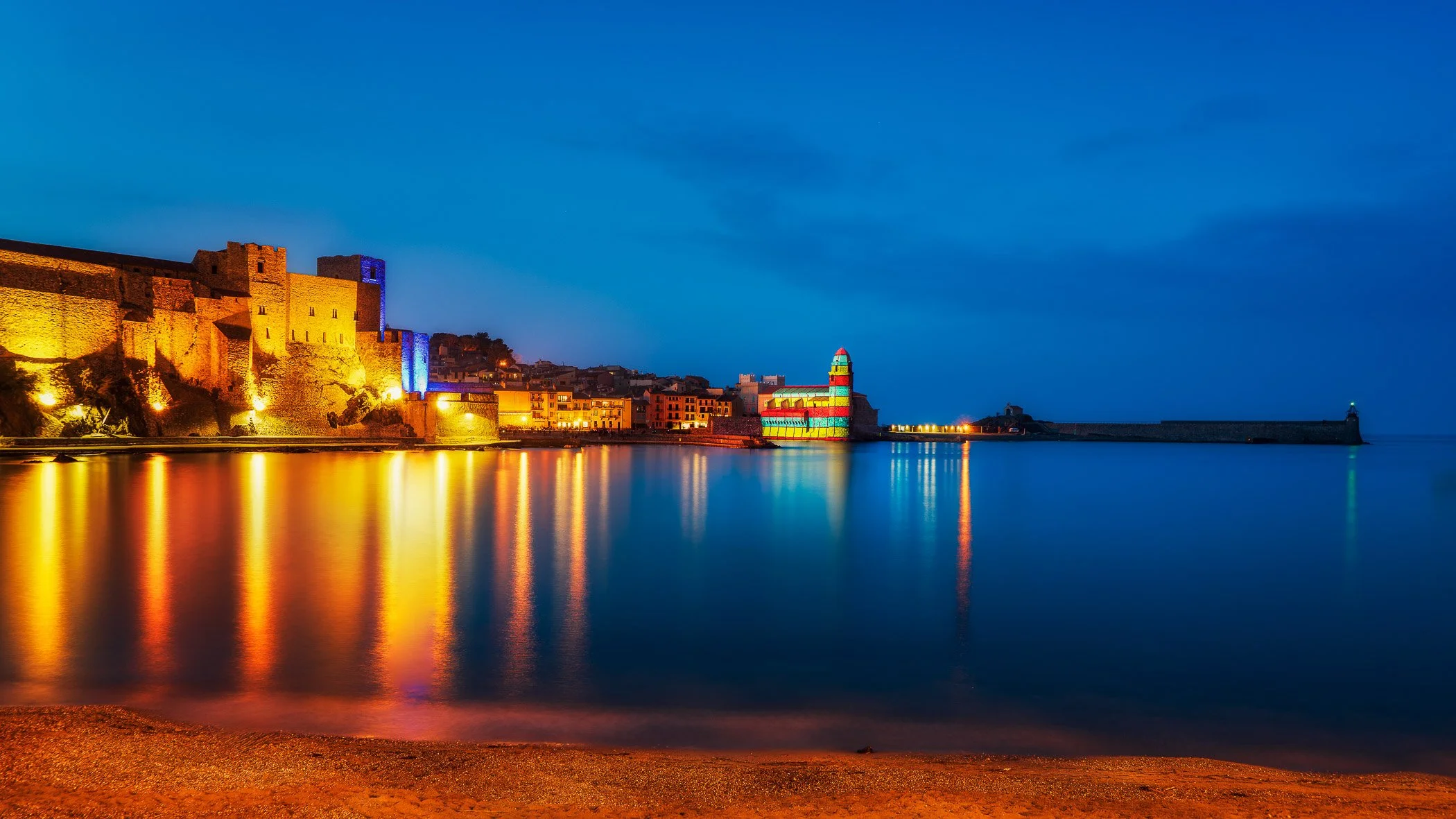 The Glow of Collioure An atmospheric photograph highlighting the warm, ambient light washing over the coastal town's colorful buildings.