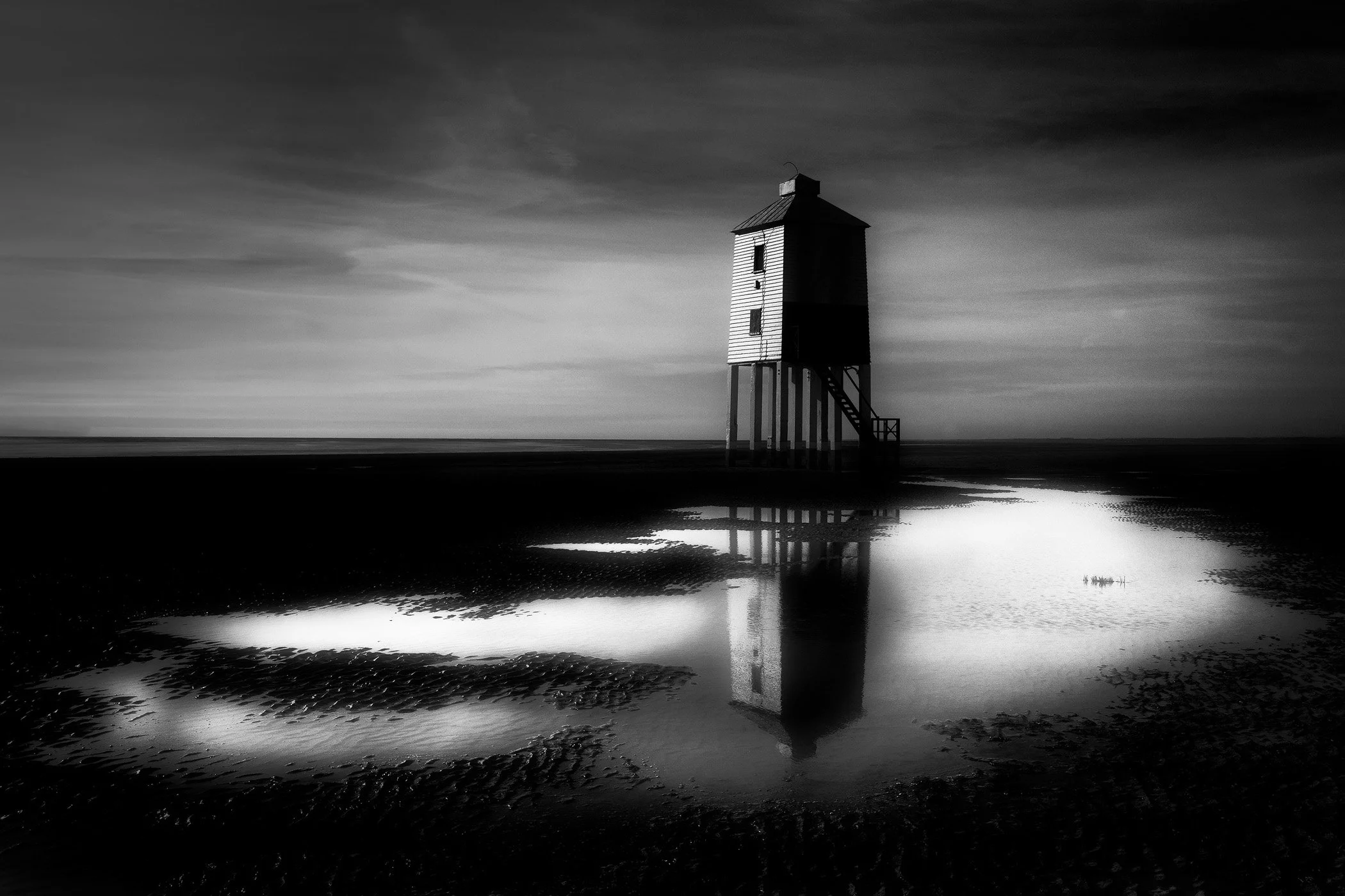 Silent Watcher at Low Tide A serene coastal composition featuring solitary shoreline structures resting quietly as the tide recedes.