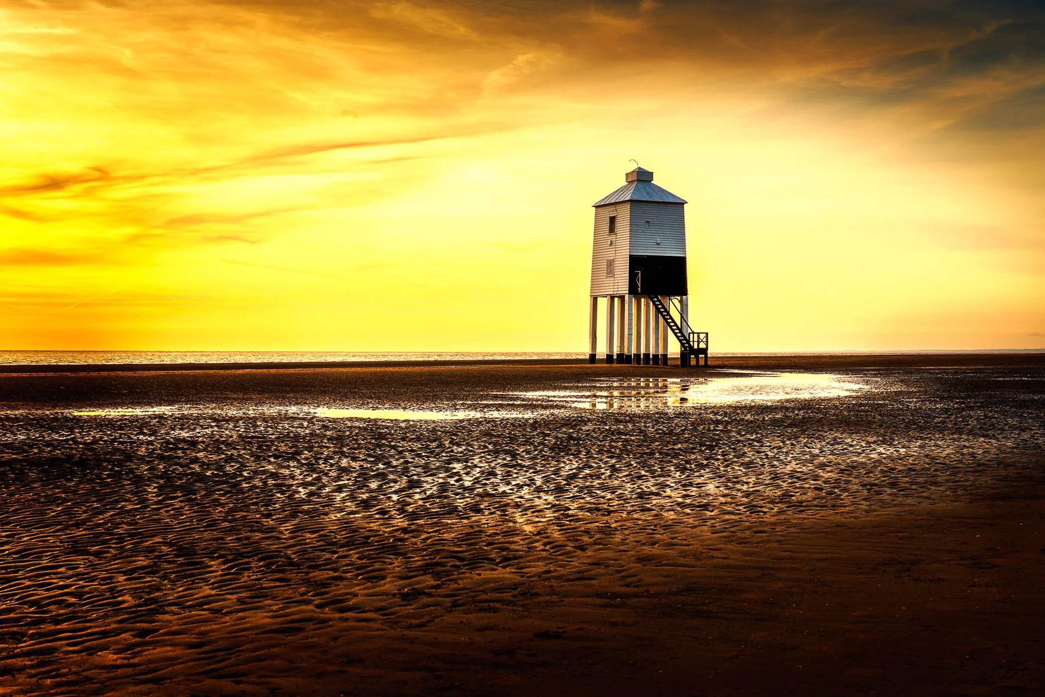 Beacon at Burnham A striking shot of the iconic Low Lighthouse standing tall against the expansive beach and glowing sky.