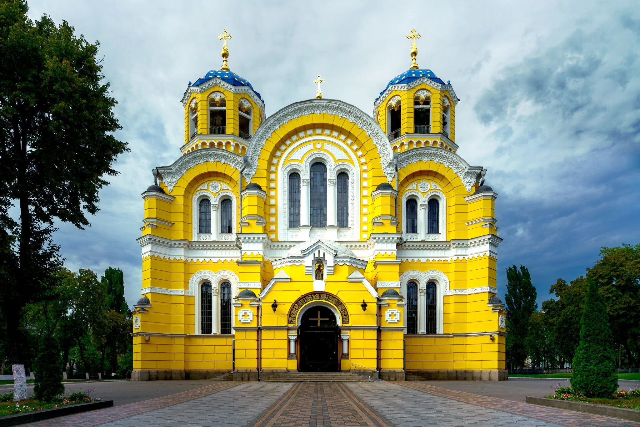 Colour photograph of Saint Volodymyr’s Cathedral in Kyiv with a bright yellow facade and blue domes beneath a clear sky