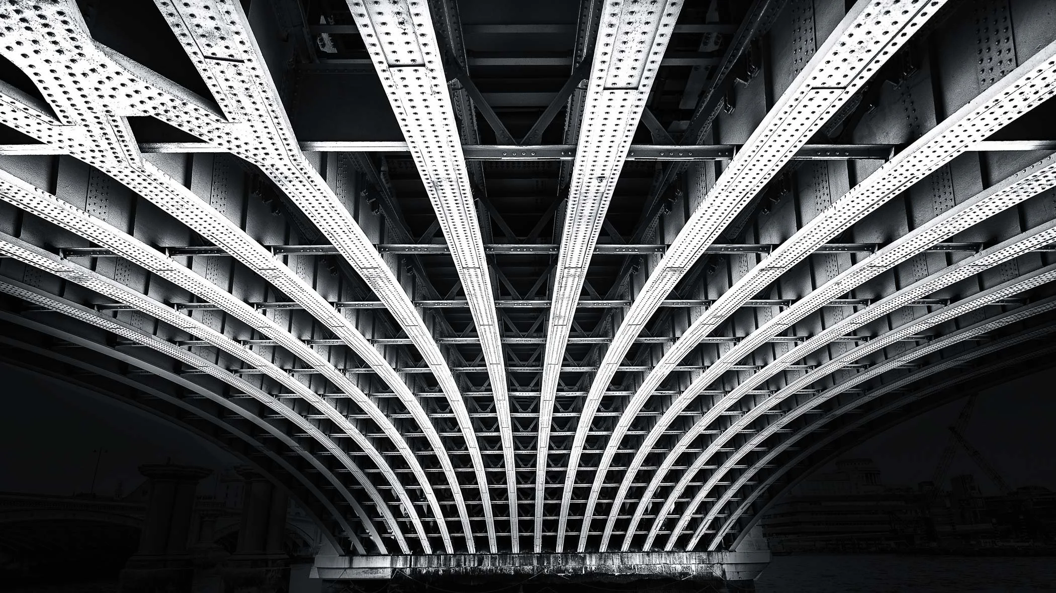 Beneath the Bridge A dramatic low-angle view showcasing the striking geometric patterns and structural ironwork of a bridge's underbelly.