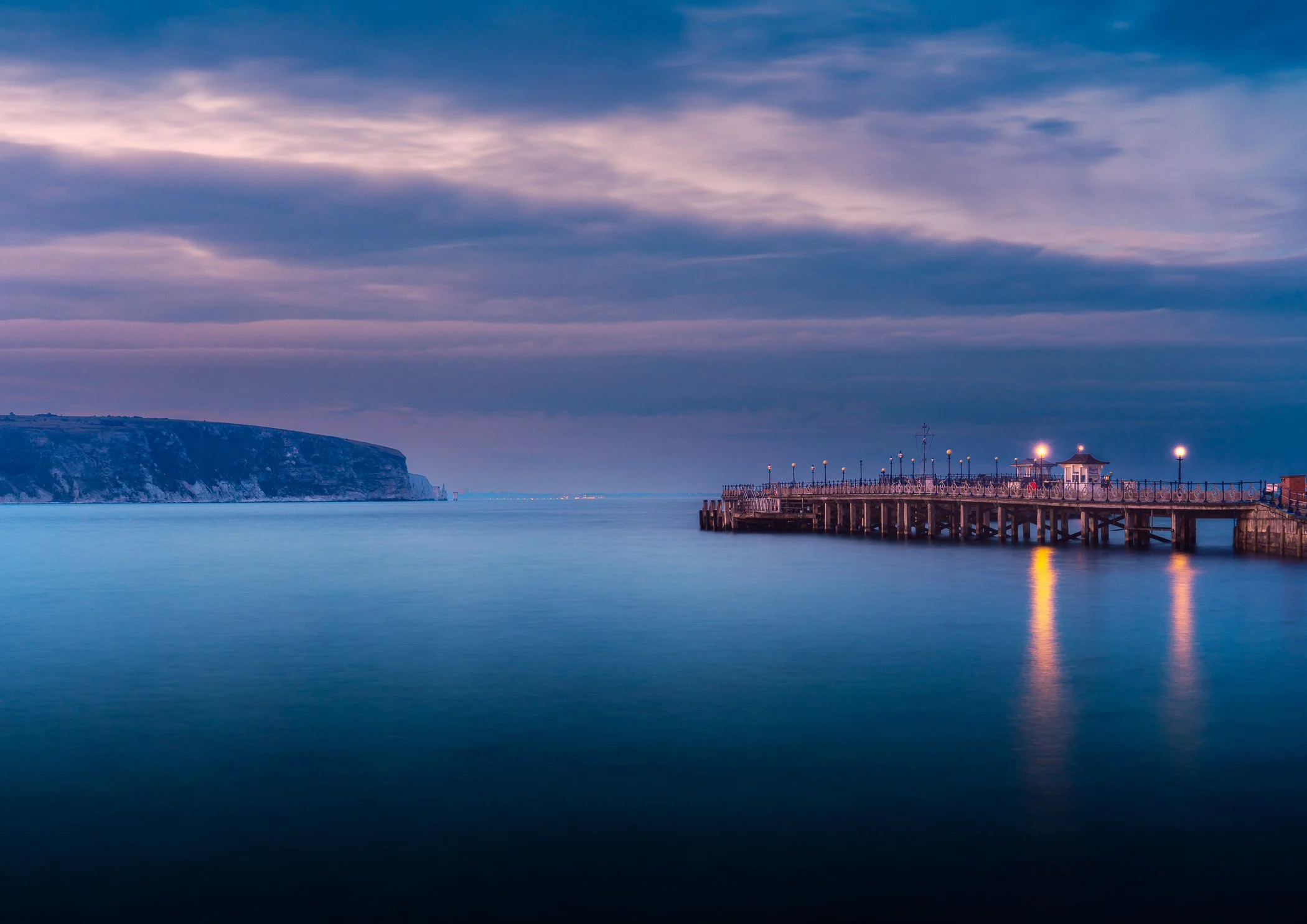 Twilight Stillness at Swanage A moody dusk photograph capturing quiet reflection and gentle light along the shoreline of Swanage.