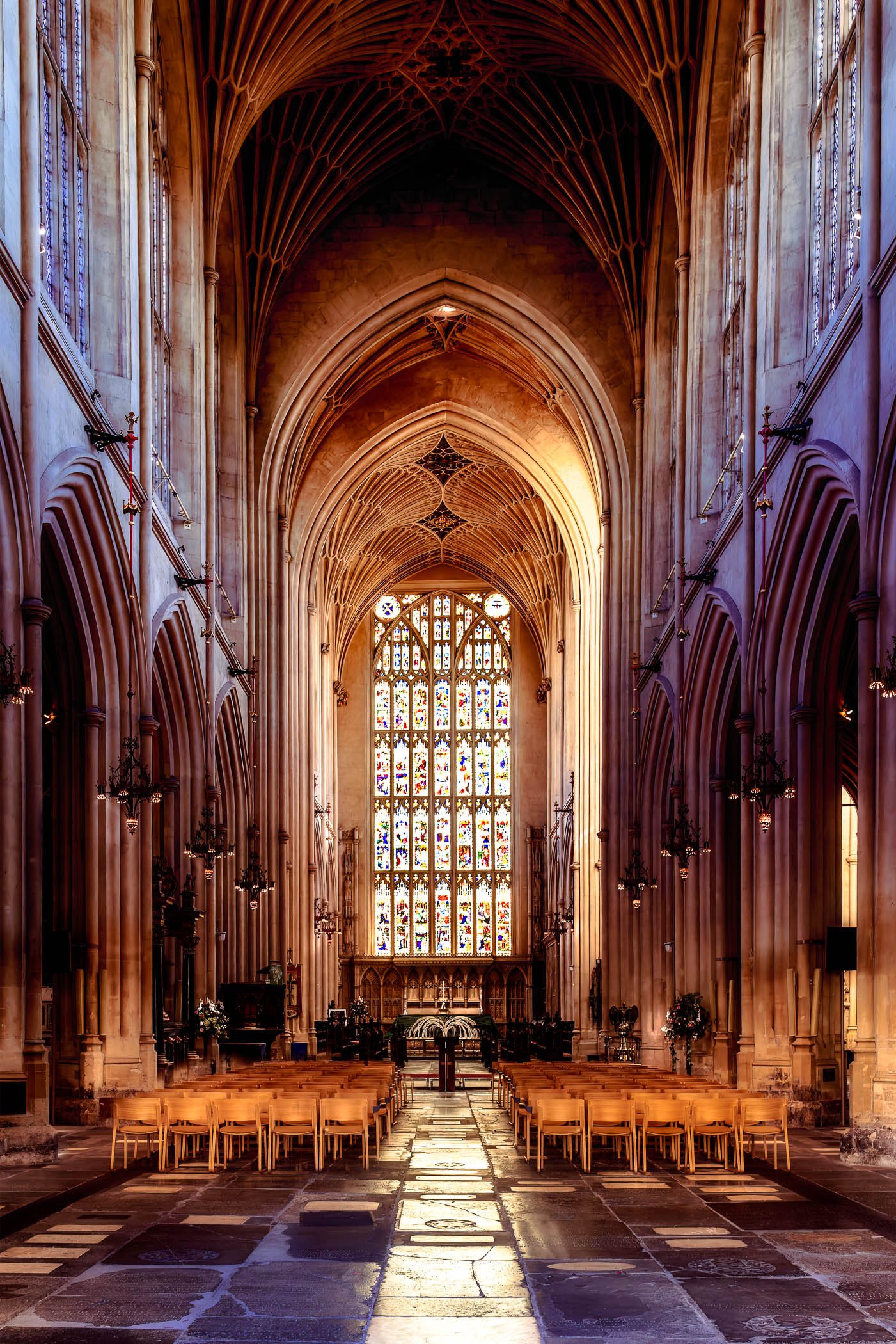 The Chancel of Bath Abbey An interior view focusing on the choir area and chancel of Bath Abbey, highlighting the intricate stained glass windows and stonework.