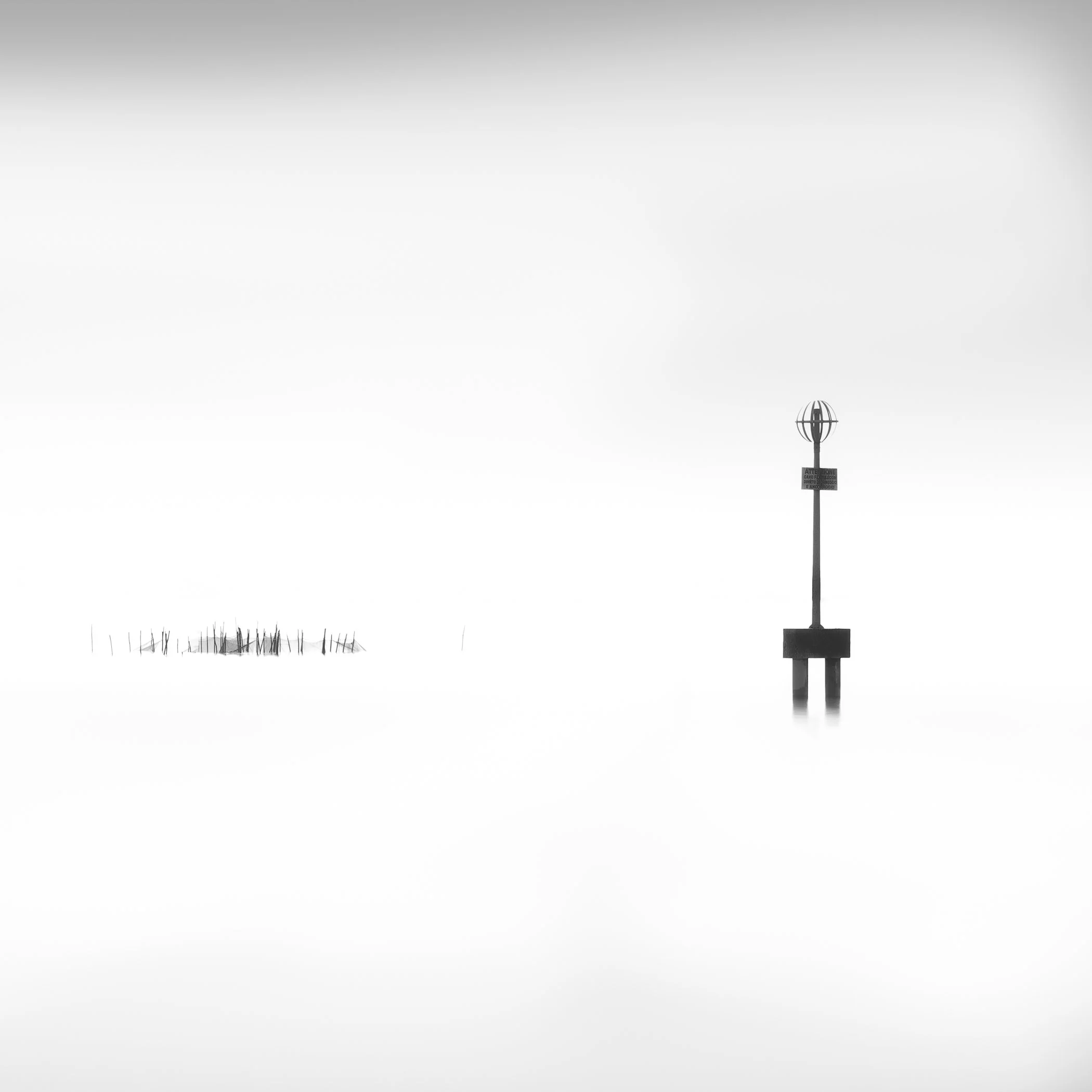 Off Burano A subtle, fog-shrouded view capturing the quiet solitude of wooden pilings in the Venetian Lagoon.