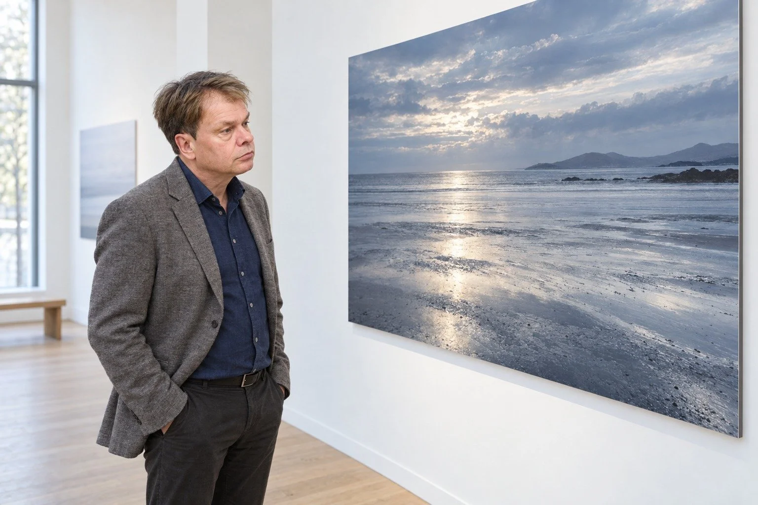 Photographer in gallery looking at seascape print