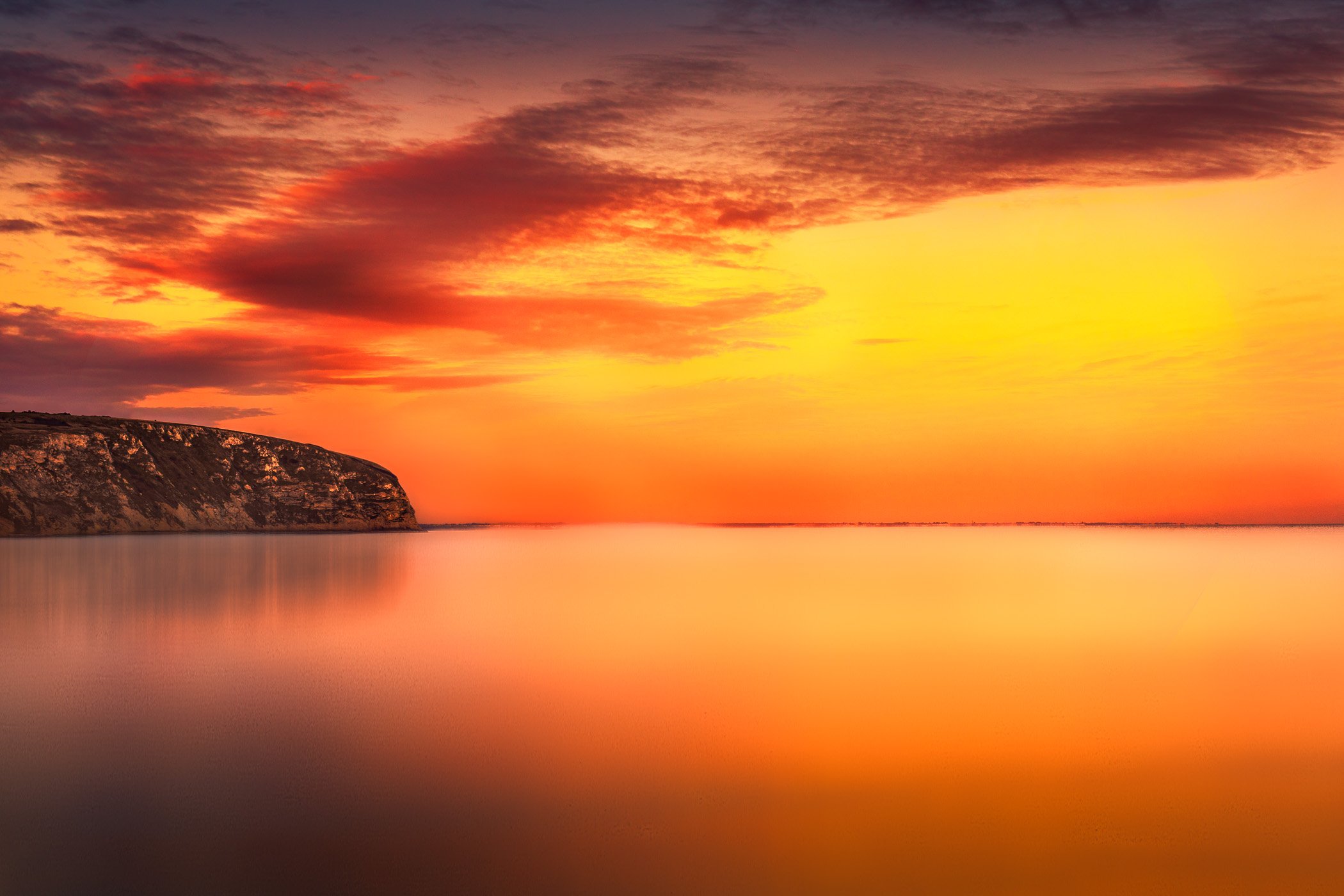 Glow at Swanage Bay A vibrant coastal photograph showcasing deep golden and pink sky hues reflecting off the bay waters.