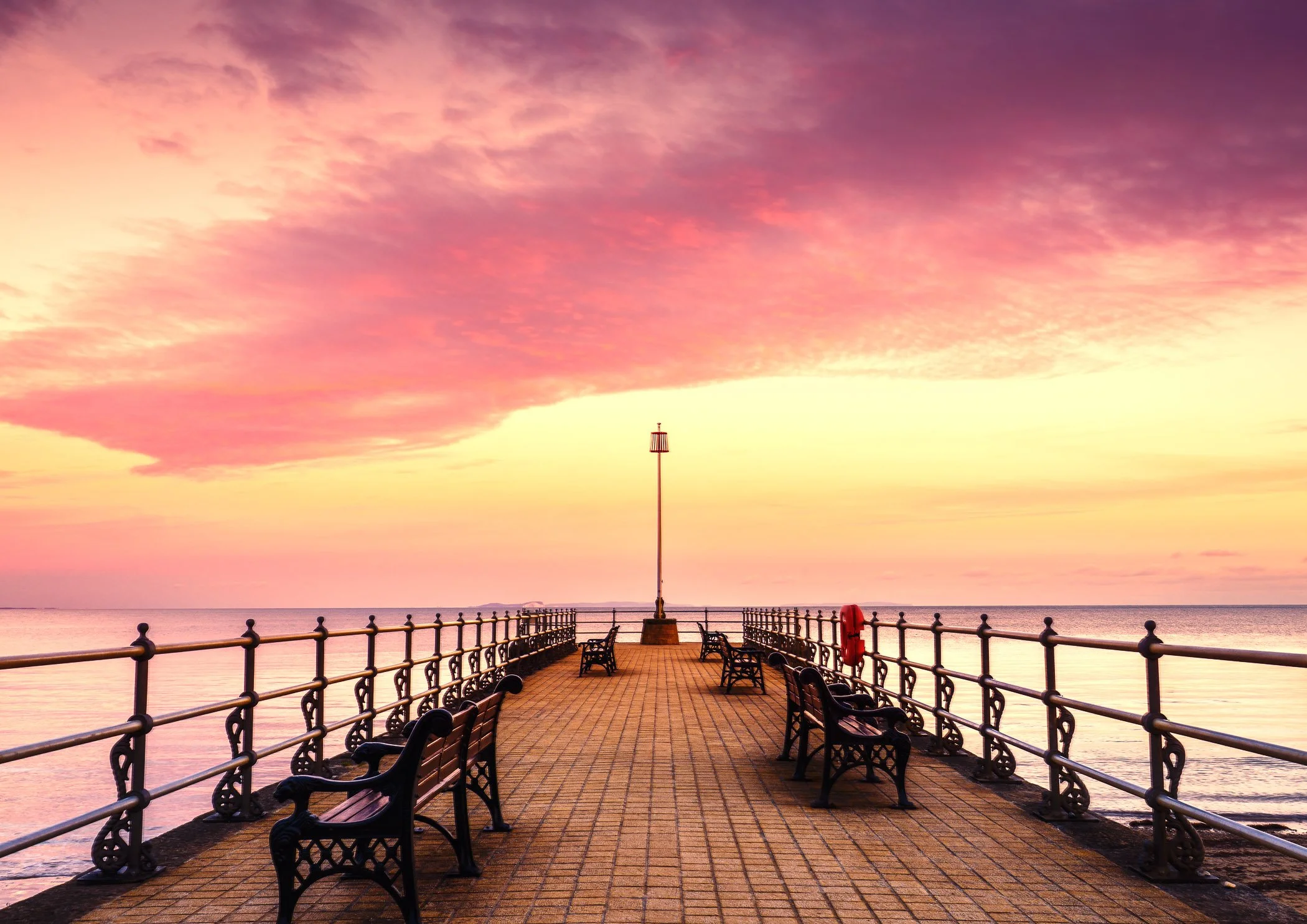 Banjo Pier Serenity A peaceful composition focusing on the historic stone pier stretching out into calm, glassy coastal waters.