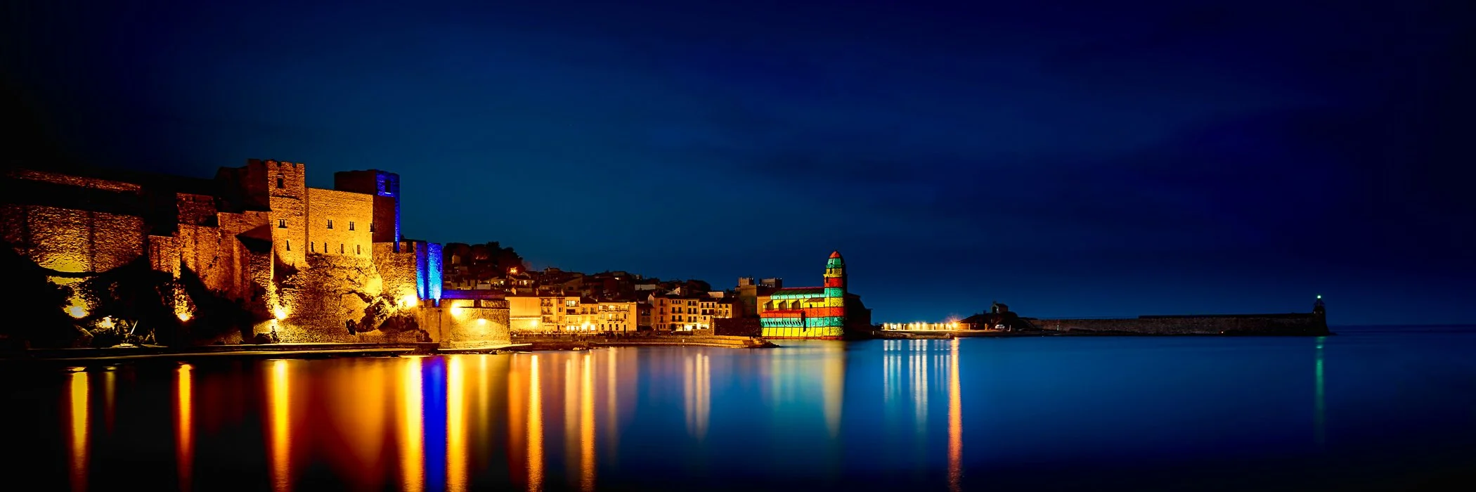 Night-time Elegance of Collioure Harbour A moody night-time view featuring glowing streetlights and gentle reflections along the historic harbor front.