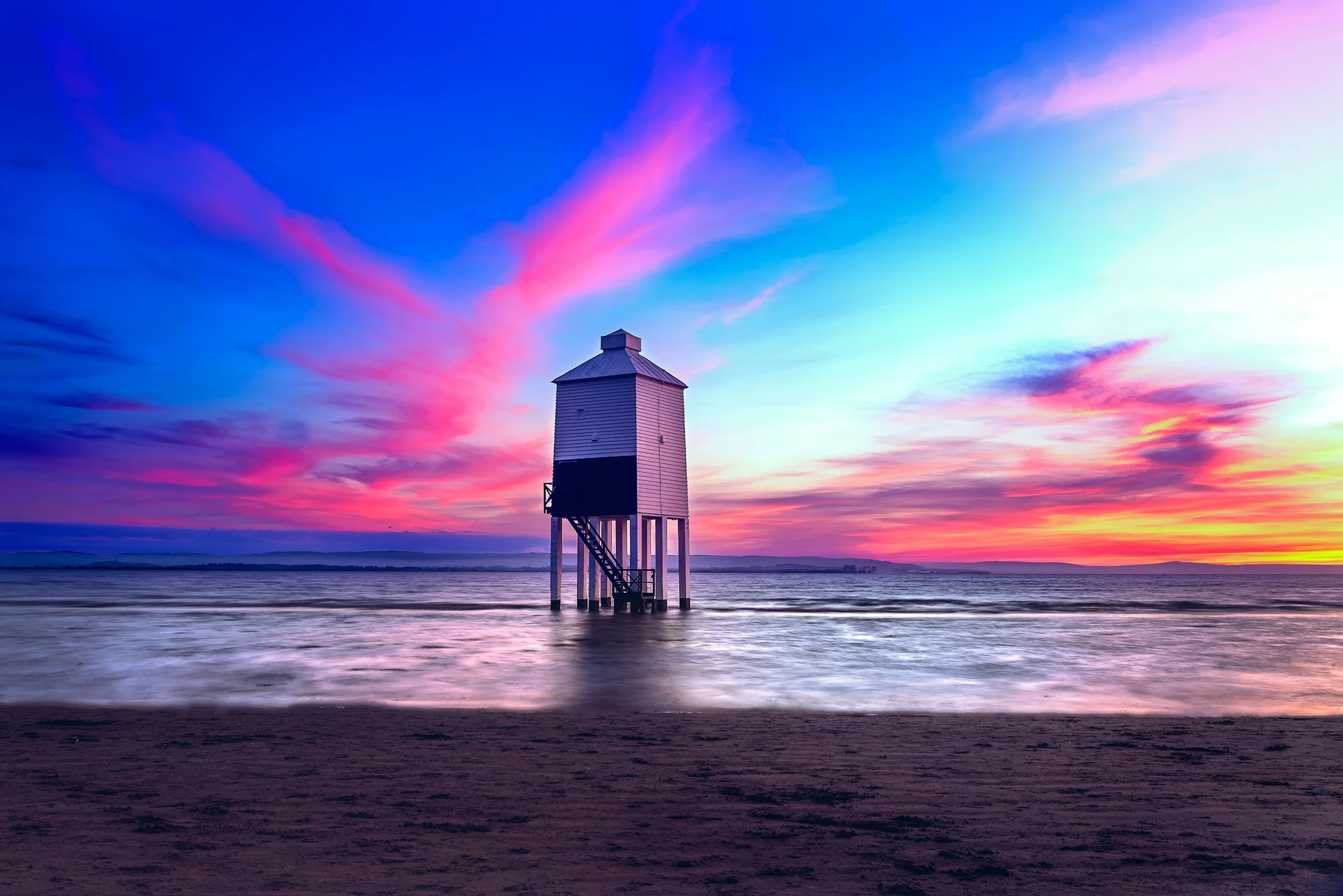 Lighthouse at Sunset A dramatic photograph capturing brilliant, colorful sunset hues lighting up the sky behind the wooden lighthouse.