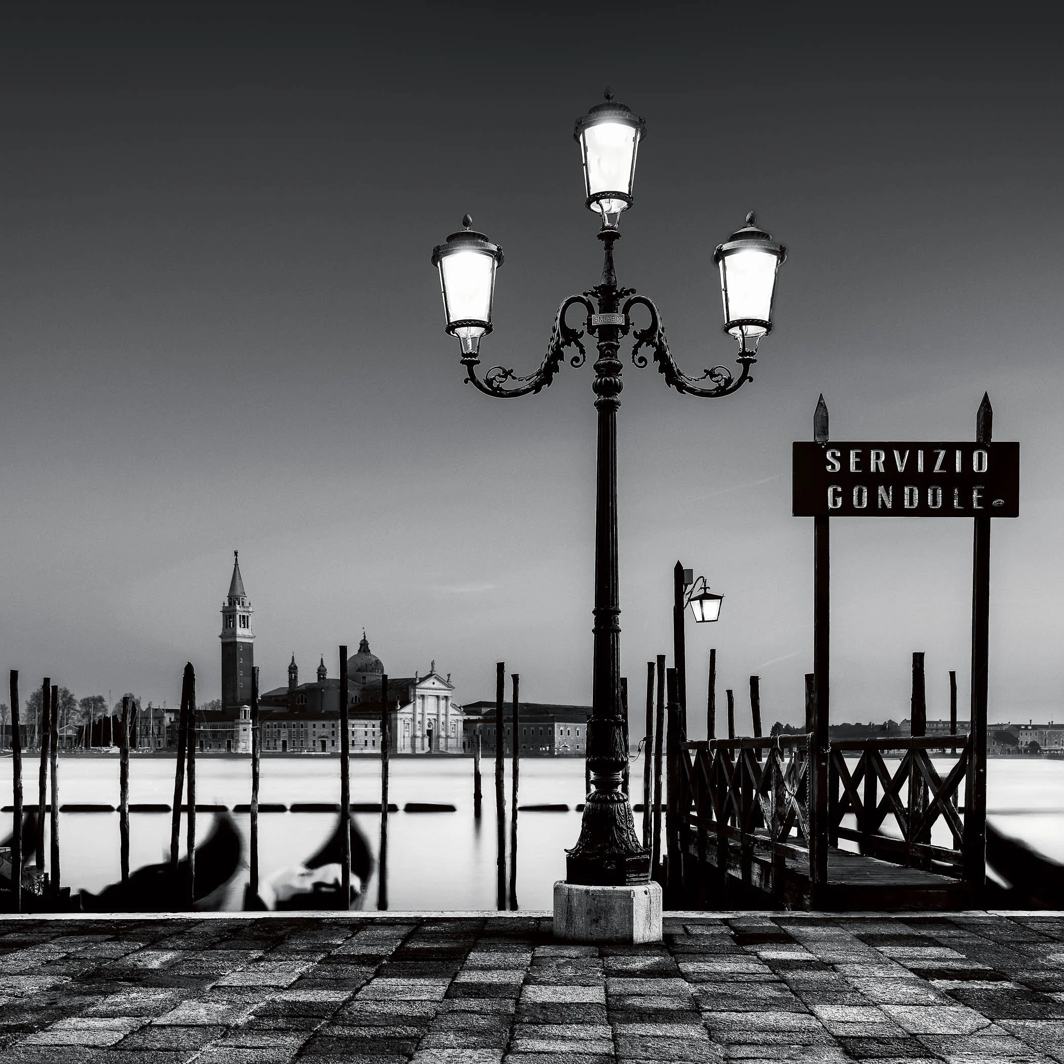 Night by the Gondola Service Soft evening light and gentle water ripples surrounding stationary gondolas along the Venetian waterfront.