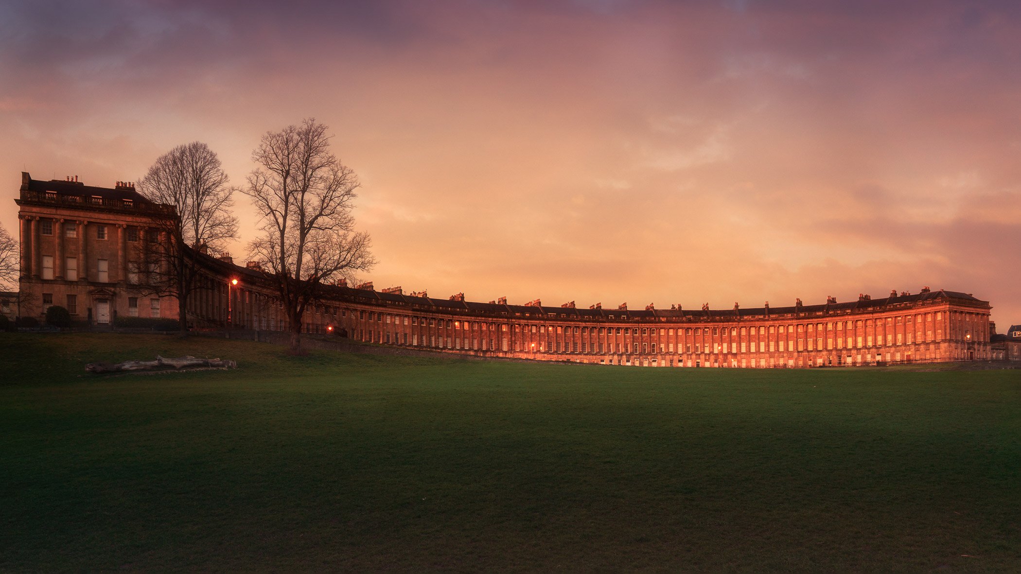 Light on the Crescent A wide-angle panoramic photograph featuring the iconic Georgian architecture of the Royal Crescent, illuminated during sunset.