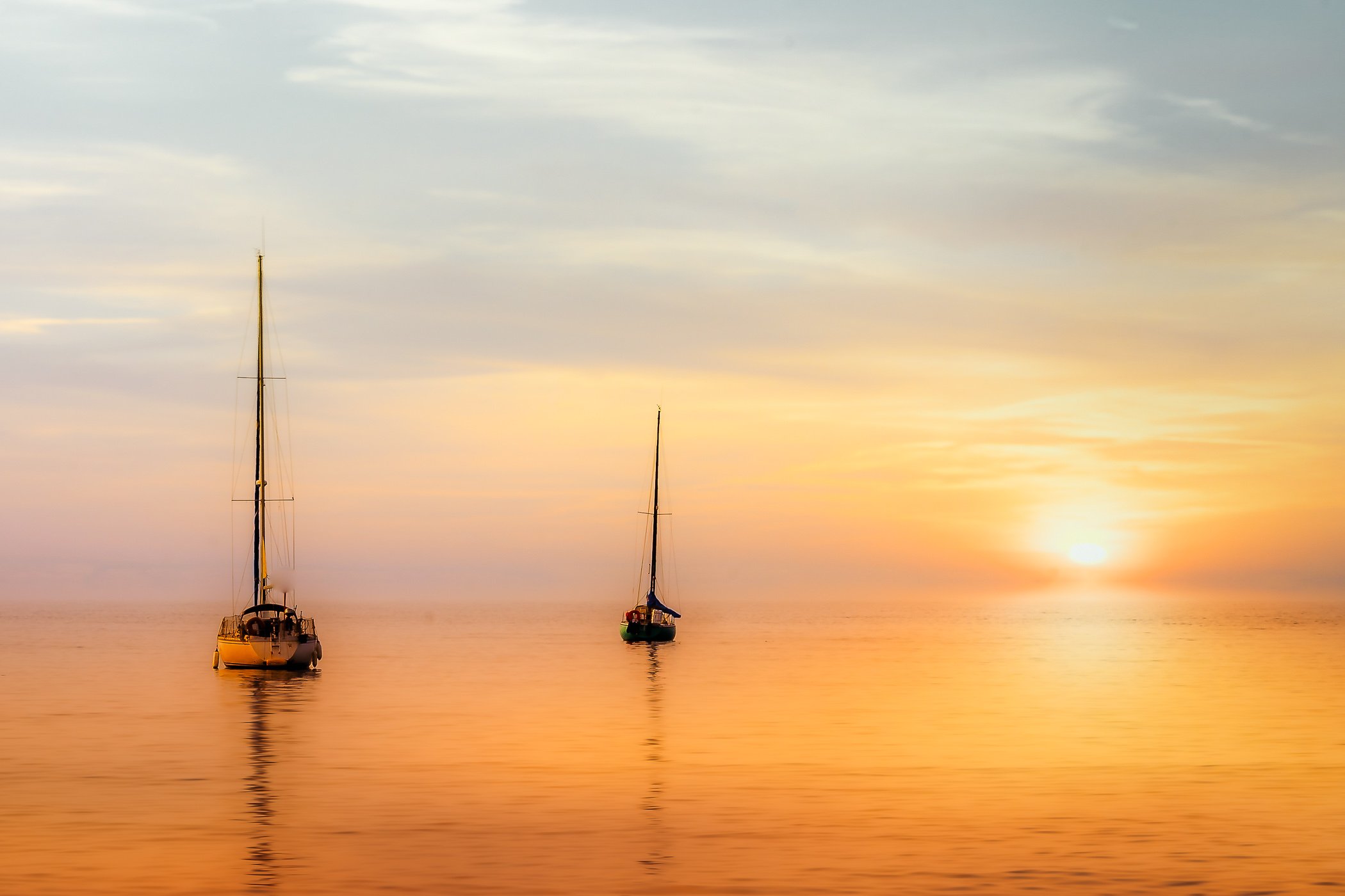 Yachts at Sunset A striking evening shot depicting sailboat silhouettes resting on calm waters framed by a glowing sunset horizon.