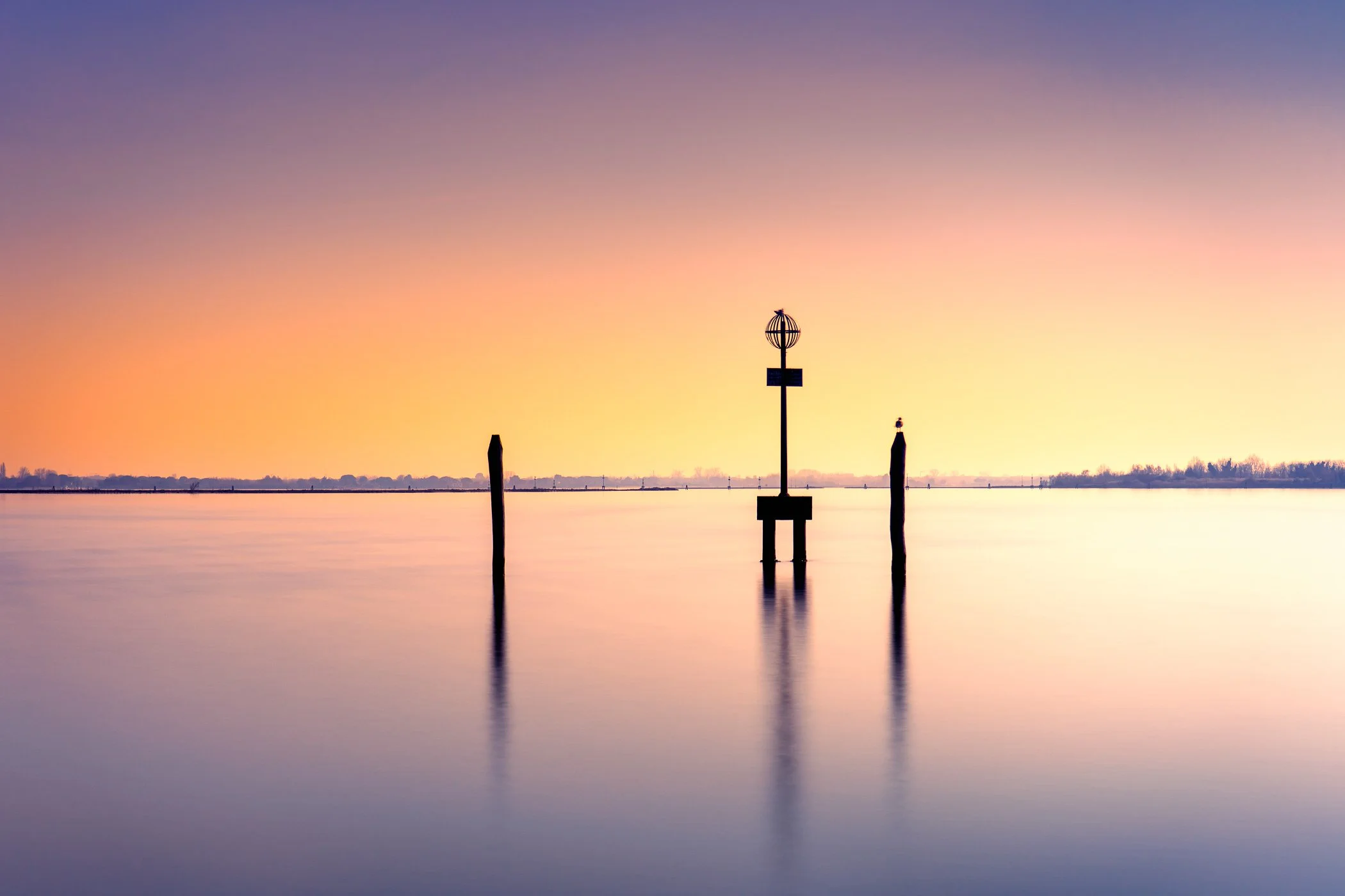 Reflections at Dawn A peaceful composition capturing mirror-like water reflections as daylight begins to break over the horizon.