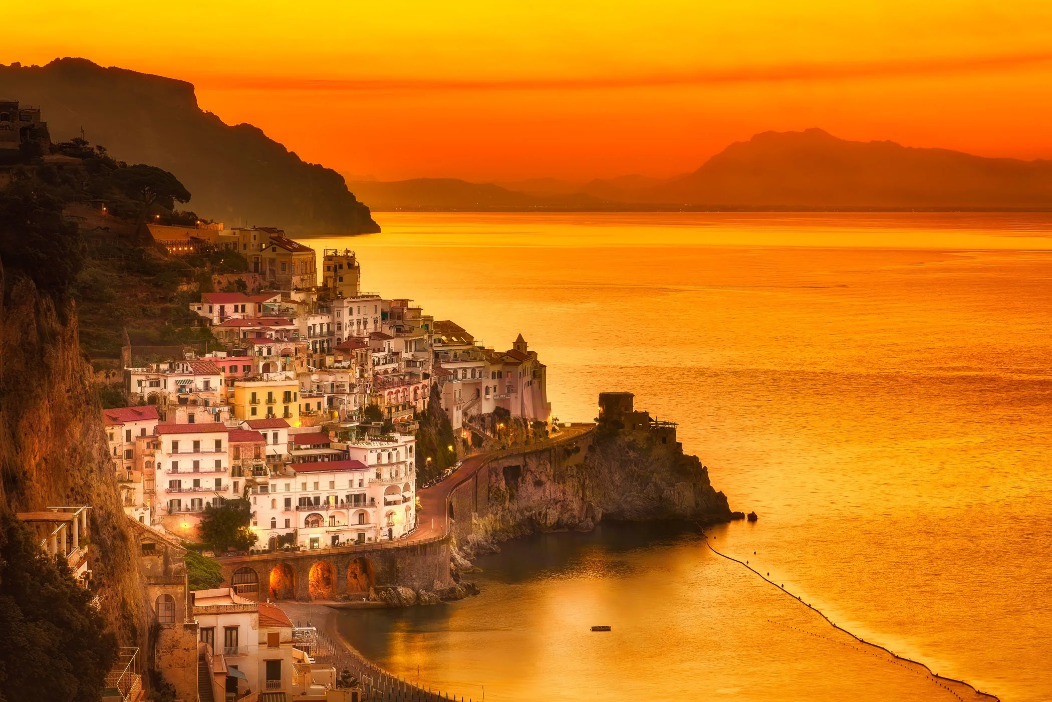 Amalfi at Sunrise An early morning view showing the warm first rays of sunlight hitting the historic coastal architecture and steep hillside terraces.