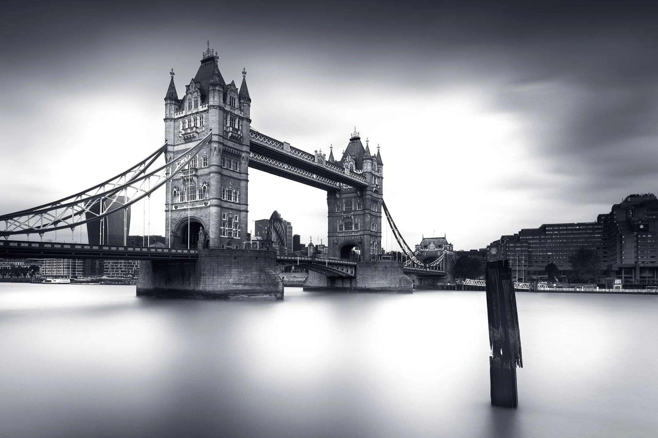 Moody Reflections of Tower Bridge A dramatic perspective of Tower Bridge featuring deep shadows, vibrant light, and mirror-like reflections on the river.