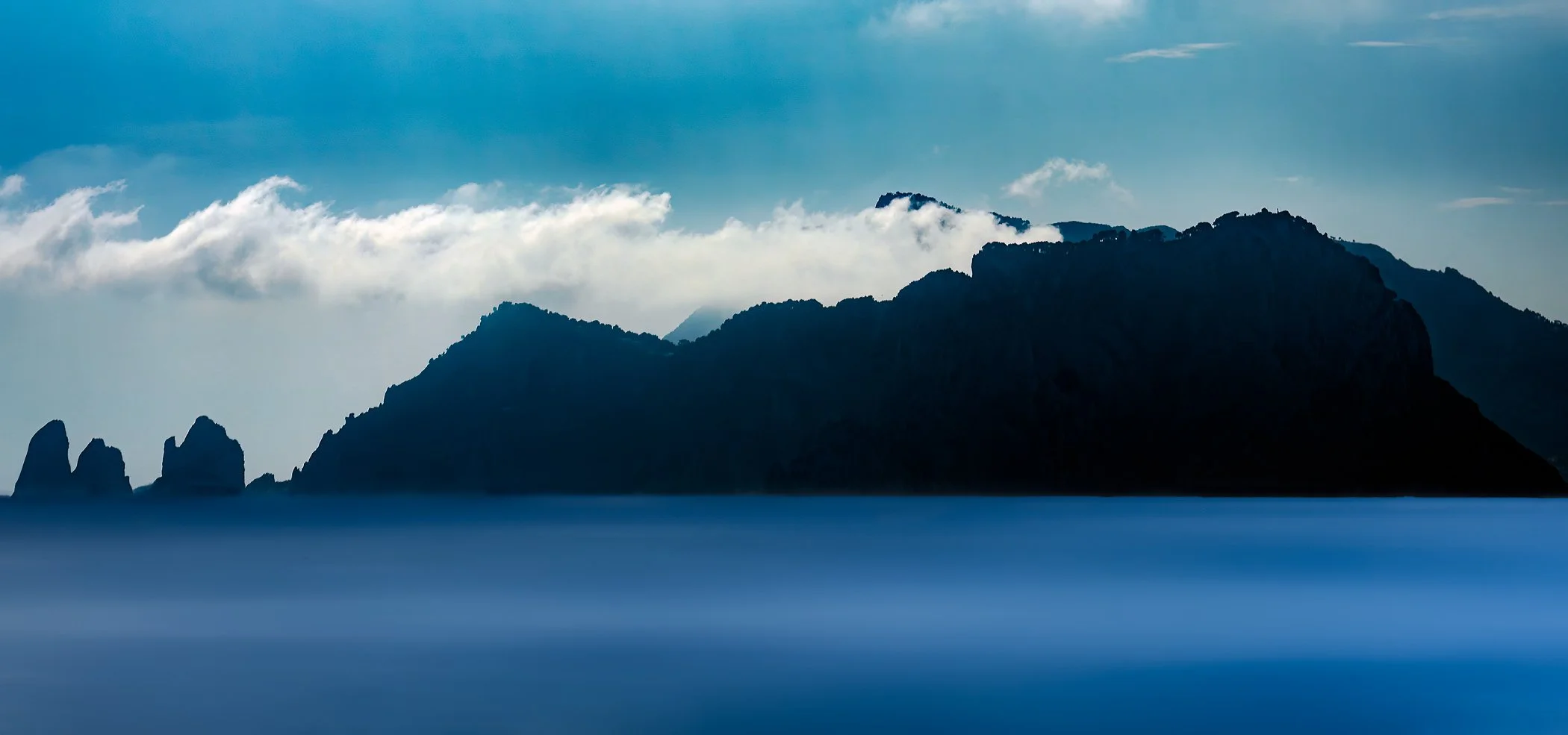 Moody Capri An dramatic, atmospheric shot of the dramatic sea stacks and rugged limestone coastline of Capri under soft, diffused light.