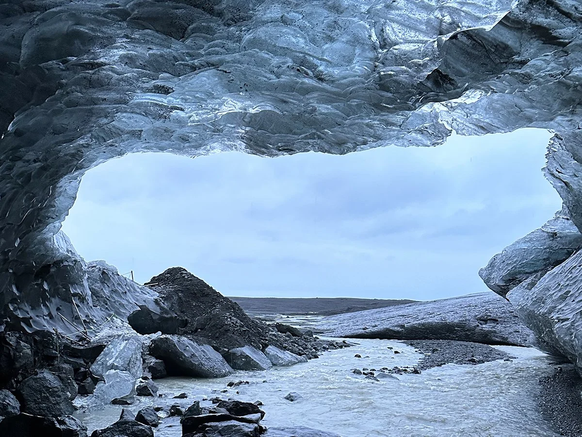 Natural ice cave beneath an Icelandic glacier with glacial meltwater flowing through