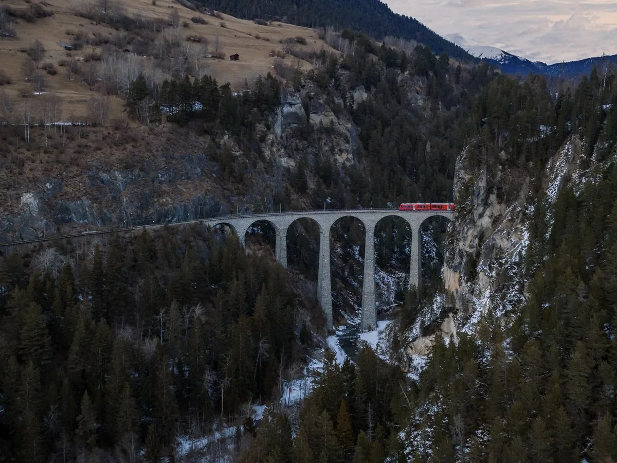 Red Swiss train crossing the Landwasser Viaduct over a deep alpine gorge