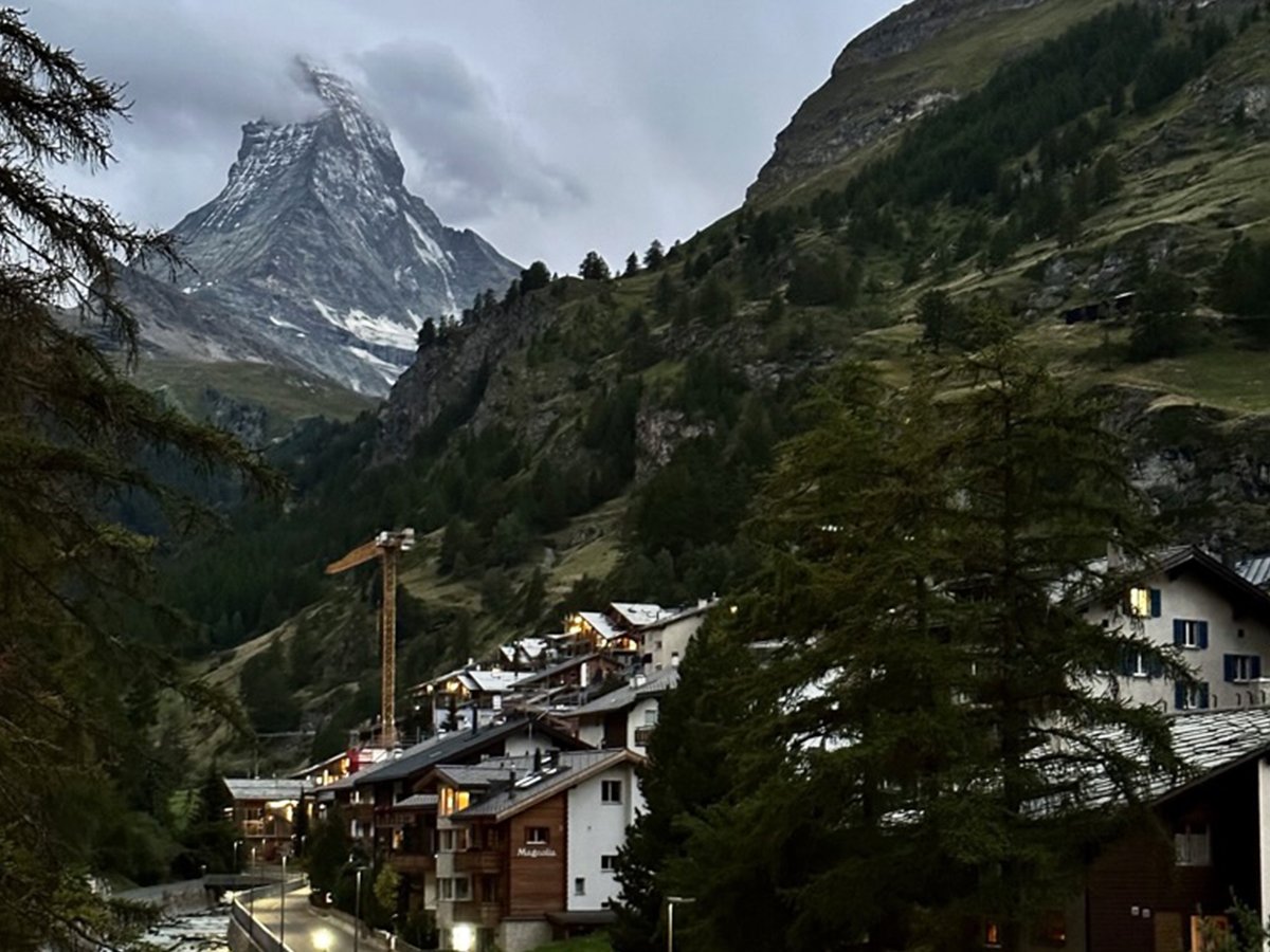The Matterhorn towering above Zermatt village with alpine buildings and forested slopes