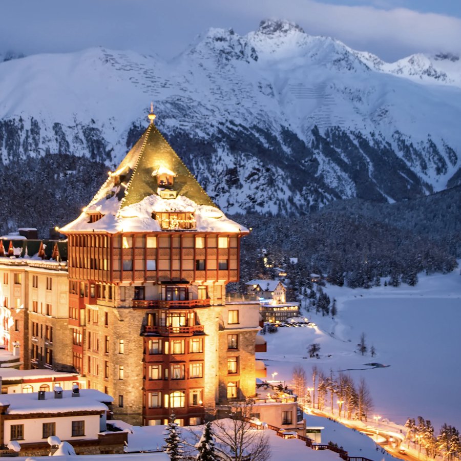 Historic Badrutt’s Palace Hotel in St. Moritz with snow-covered alpine mountains behind the hotel.