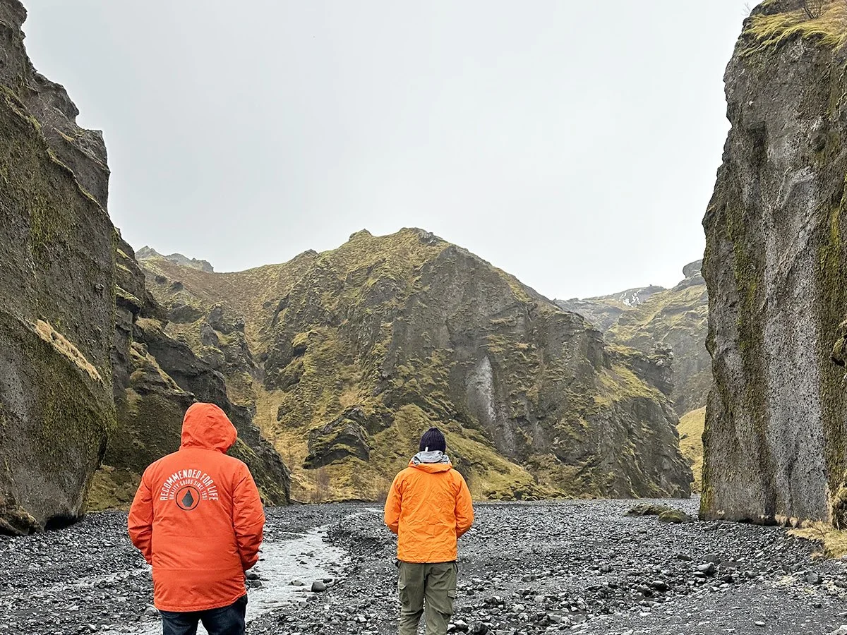 Travelers walking through a volcanic canyon landscape in Iceland