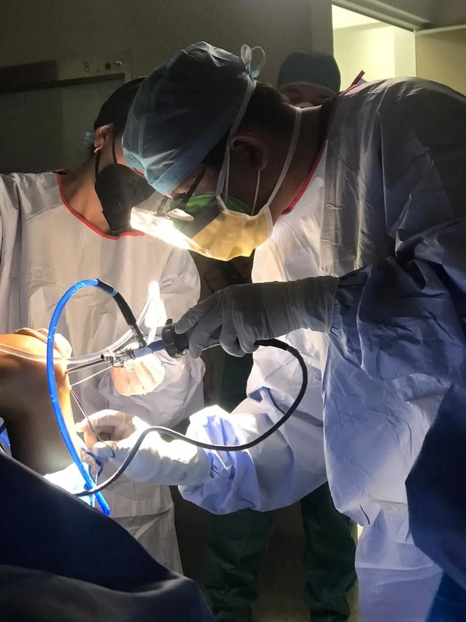 Personal médico realizando una cirugía en un quirófano con instrumentos y equipo de protección.