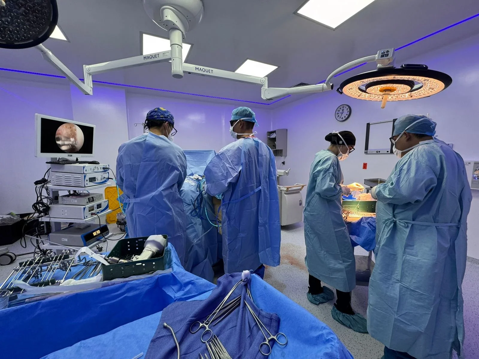 Personal médico en una sala de cirugía realizando un procedimiento quirúrgico con instrumentos y equipos médicos.