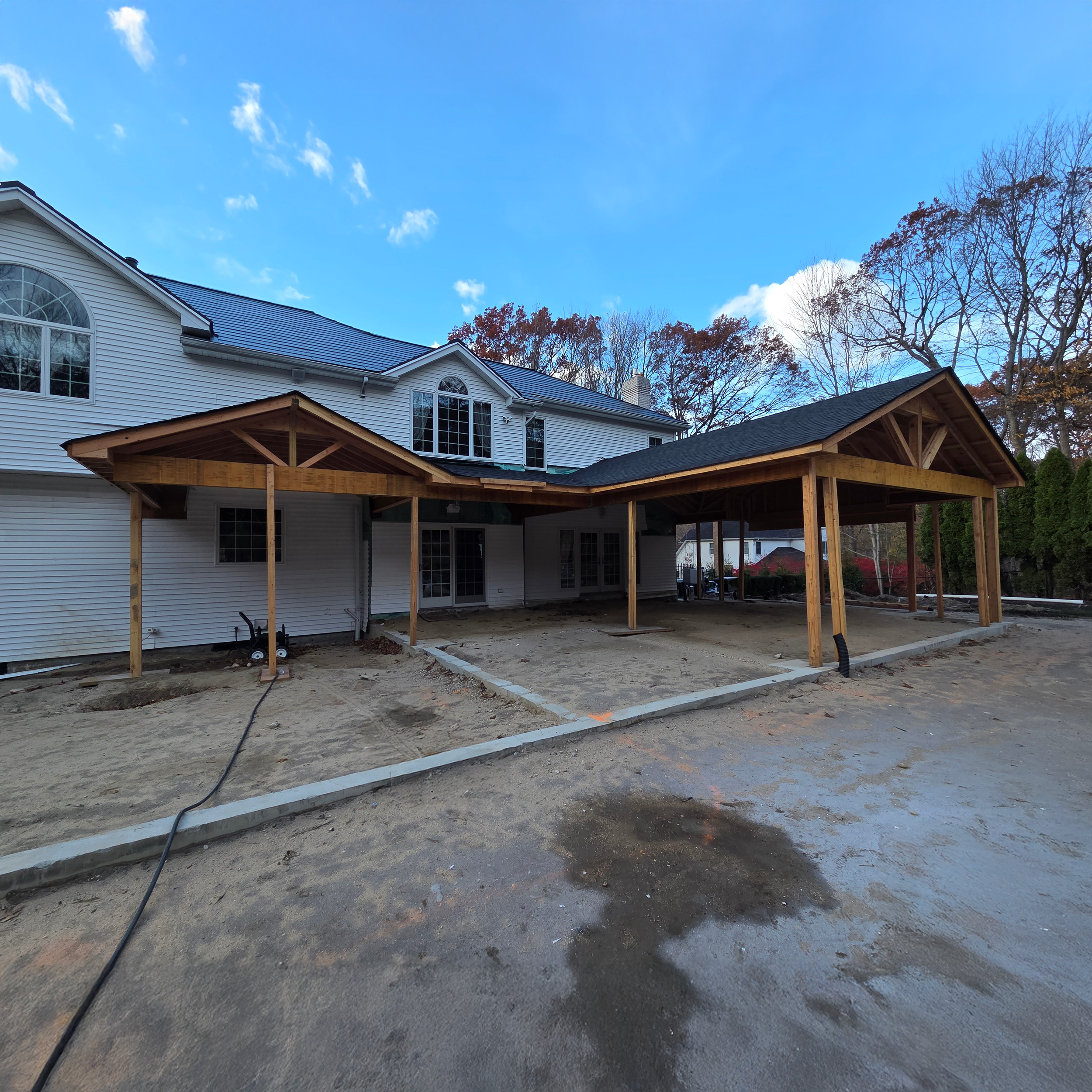 Backyard renovation under construction in Fort Salonga, NY showing new covered patio framing designed by Americana Architects.