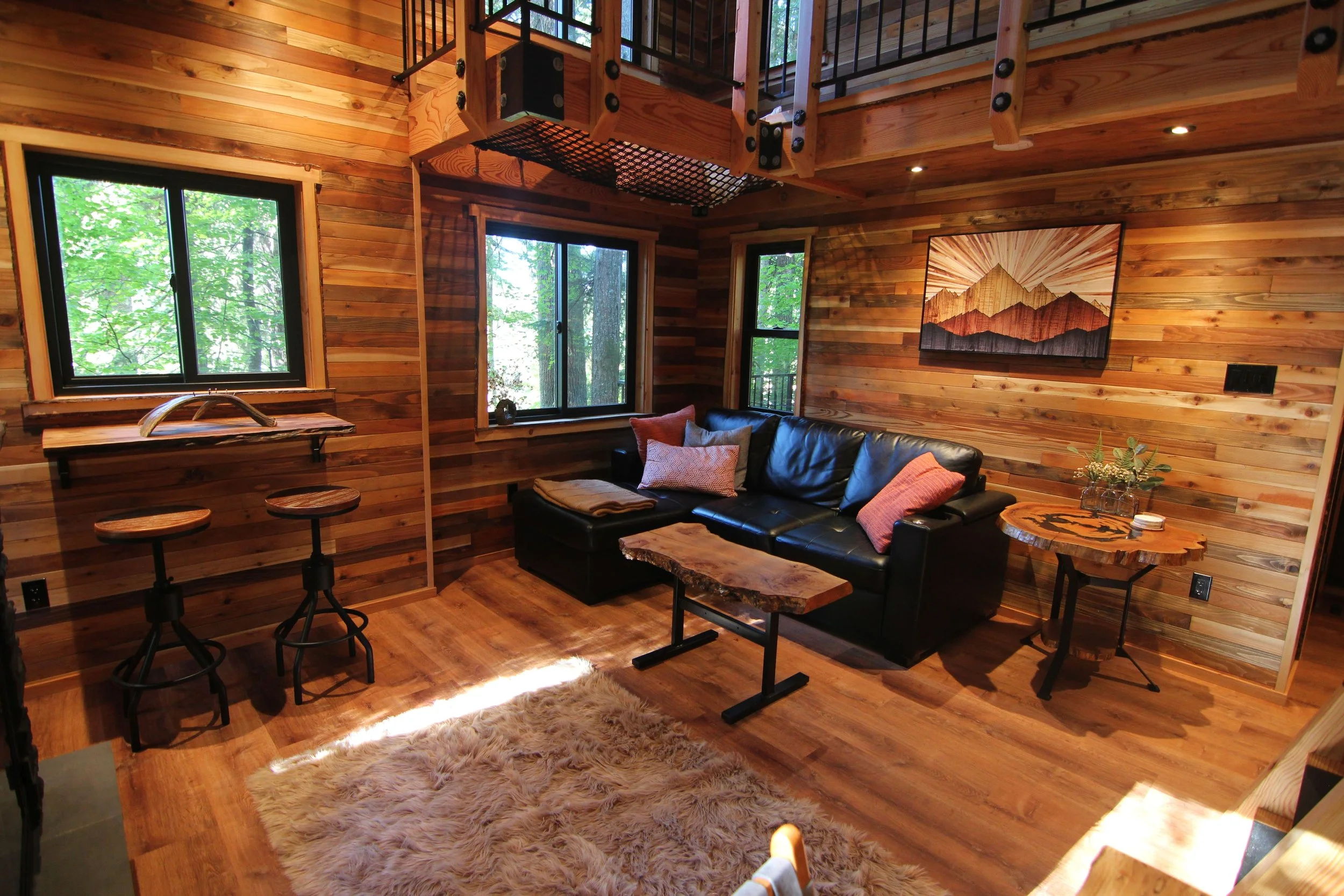 Luxury treehouse interior living room with loft and custom wood detailing designed by treehouse architect Americana Architects.