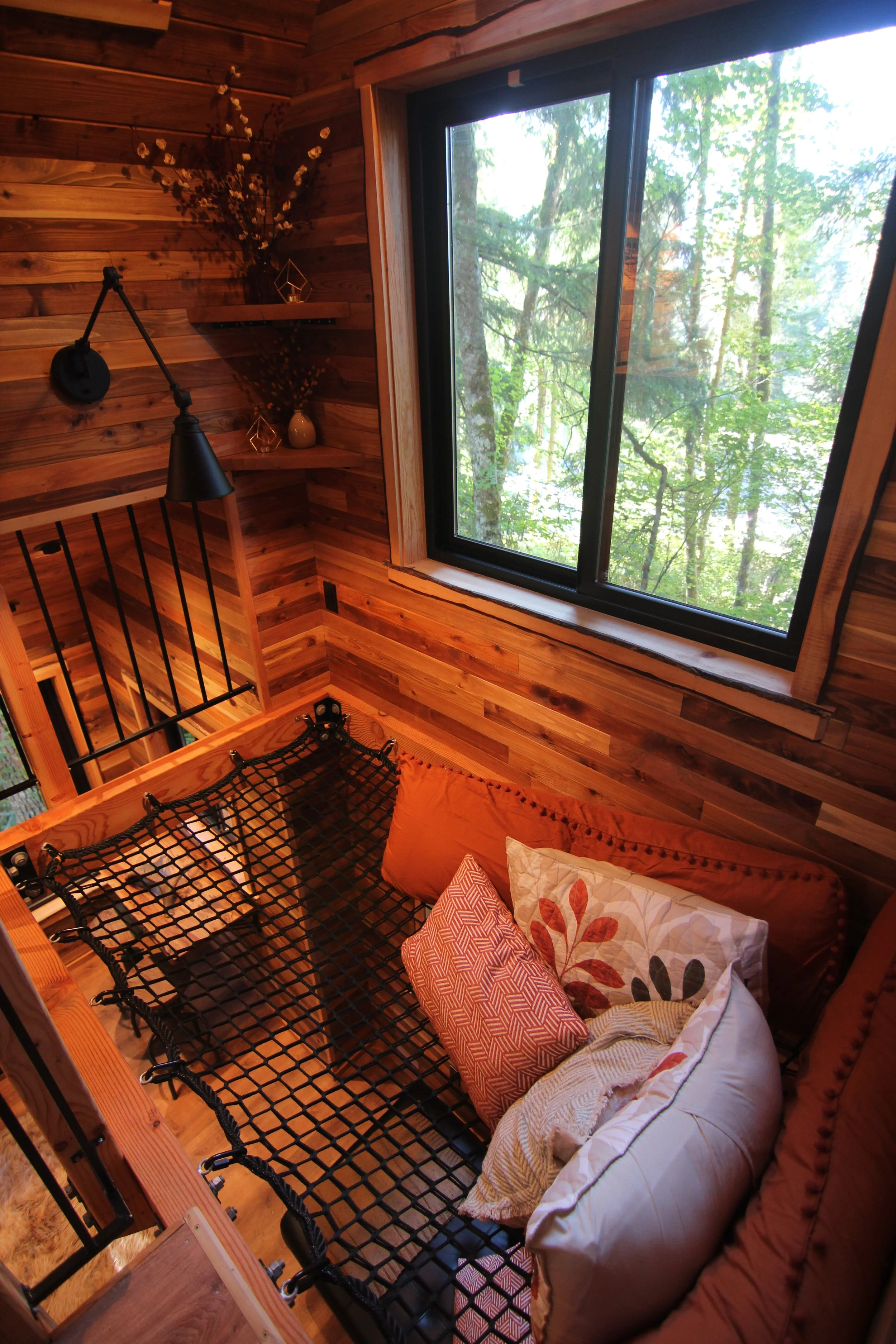 Custom treehouse loft lounge with net seating and forest views designed by professional treehouse architect Americana Architects.