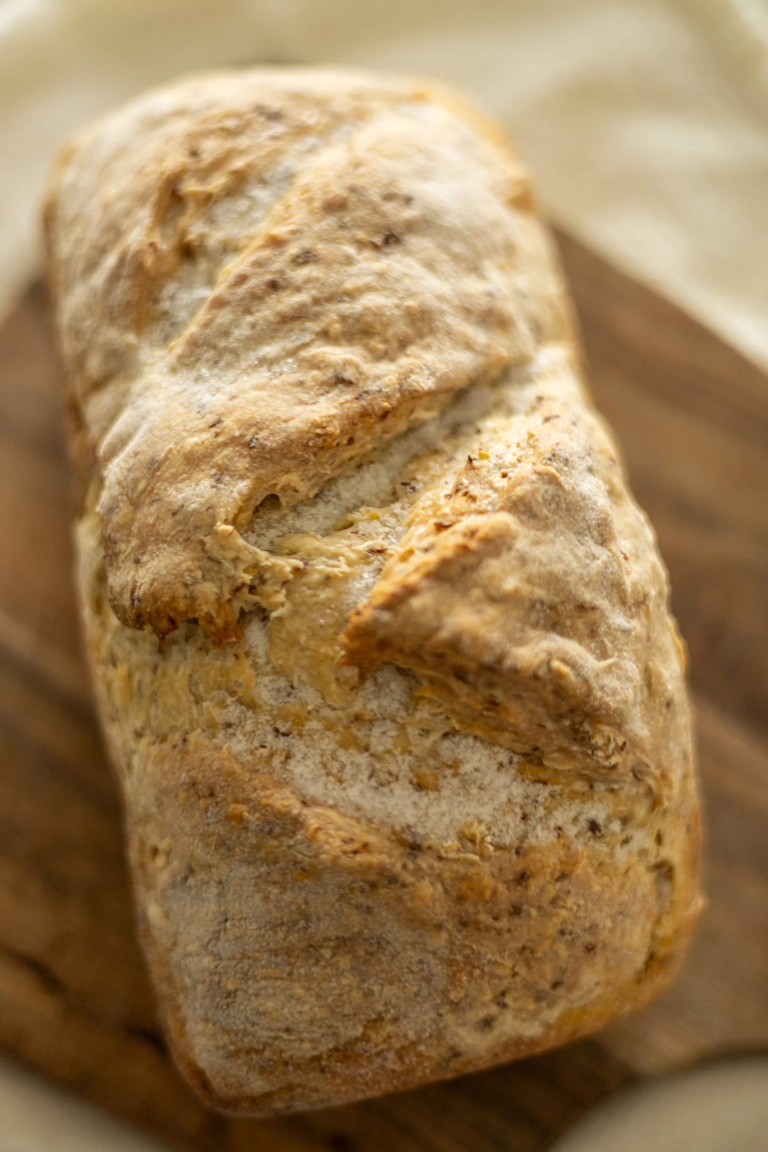 Close-up of a loaf of crusty sourdough bread on a wooden surface with small frozen ice crystals on top
