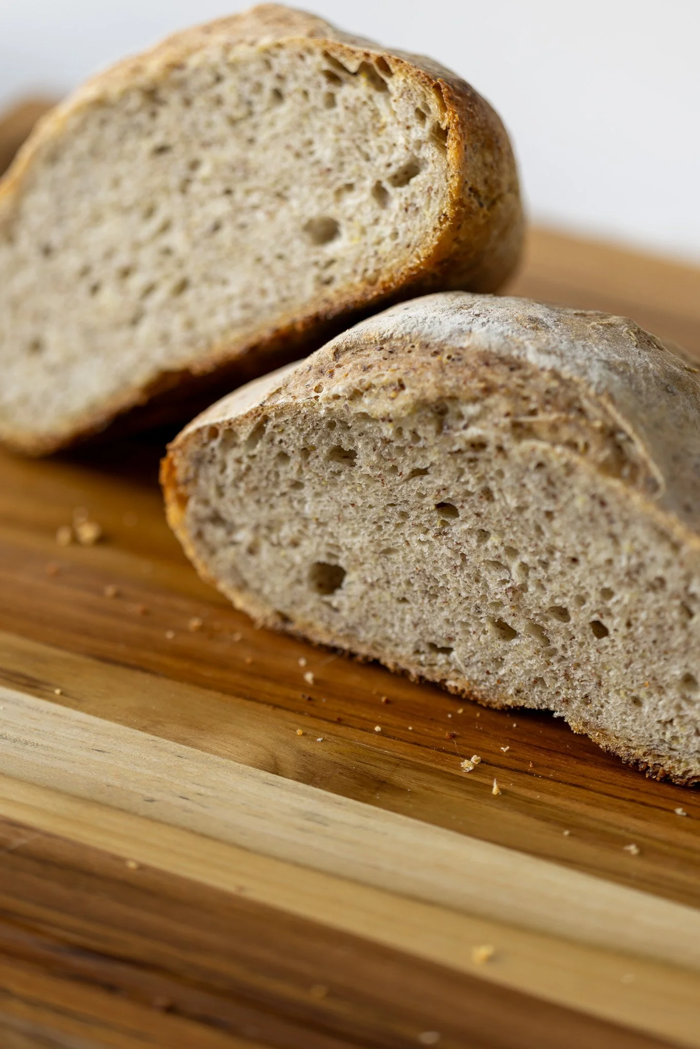 Close-up of Arctic Sourdough sliced rustic whole wheat bread on a wooden cutting board.