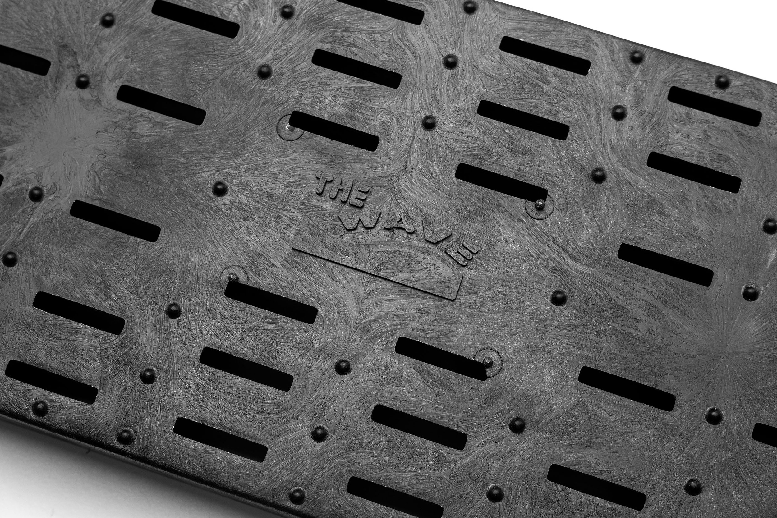 Close-up of a metallic grate with engraved text 'THE WAVE' in the center.