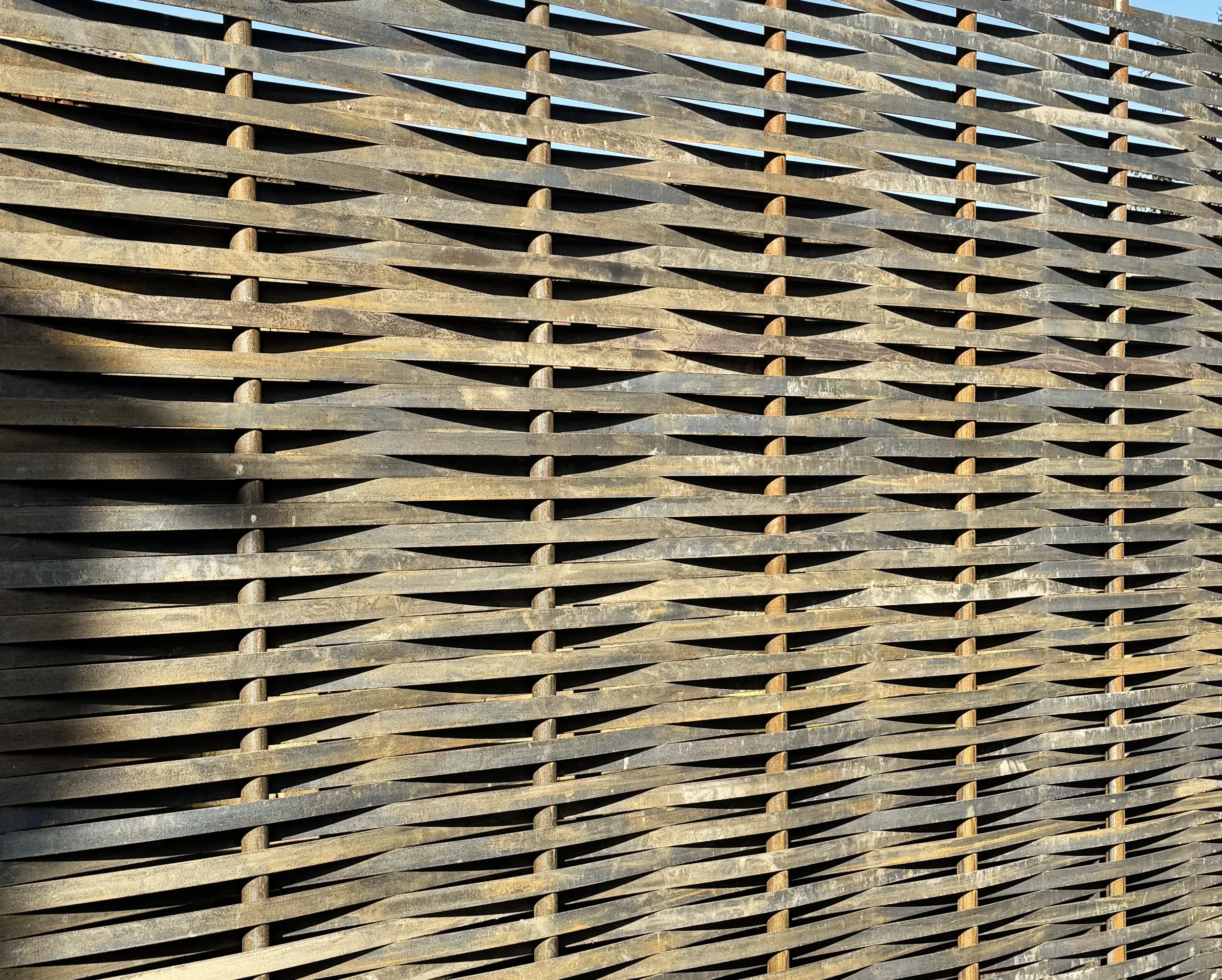 Close-up of a woven wooden fence with a pattern of horizontal and diagonal slats.